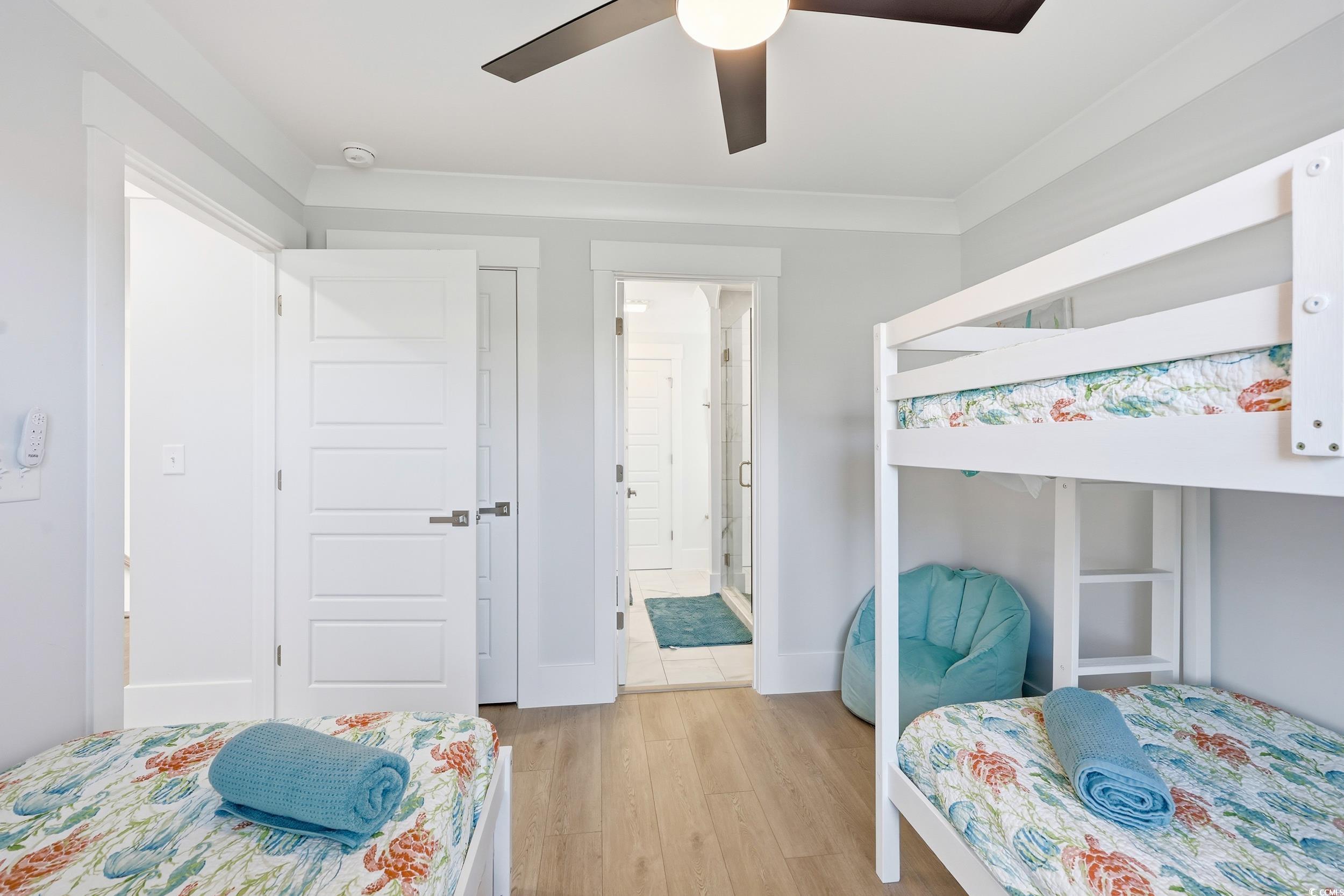 Bedroom with wood finished floors, ceiling fan, and connected bathroom