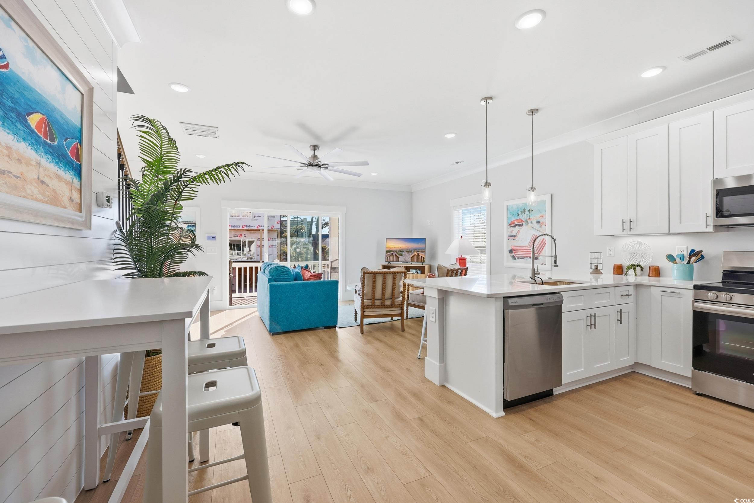 Kitchen featuring white cabinetry, stainless steel appliances, open floor plan, pendant lighting, and a peninsula