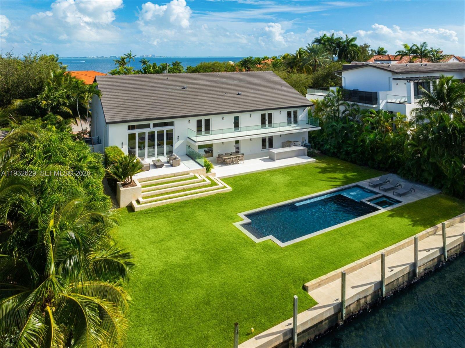Located in the gated Sunrise Harbor community, this completely renovated waterfront contemporary estate offers 7,435 total SF on a 14,500 SF lot with 100 feet of canal frontage and no bridges to Biscayne Bay. The 6-bedroom, 6 full and 1 half-bath home showcases a dramatic triple-height living room, panoramic water views, custom millwork, Lutron smart lighting, and high-impact glass throughout. A chef’s kitchen features bespoke cabinetry, leather finish marble countertops, Sub-Zero and Miele appliances, and glass-enclosed cabinets. The expansive primary suite includes vaulted ceilings, a private balcony, and a spa-like bath. Newly added flex and wellness spaces open up right onto the backyard with ample windows/natural light, including a bedroom/gym, cabana bath, steam shower, sauna, cold plunge and separate HVAC. Outdoors, enjoy lush landscaping, a circular driveway, heated saltwater pool with spa, expansive terraces, summer kitchen, glass railings, and a concrete dock with deep water docking for large boats/yachts—perfect for seamless indoor-outdoor waterfront living near top schools, Coconut Grove, and Coral Gables.