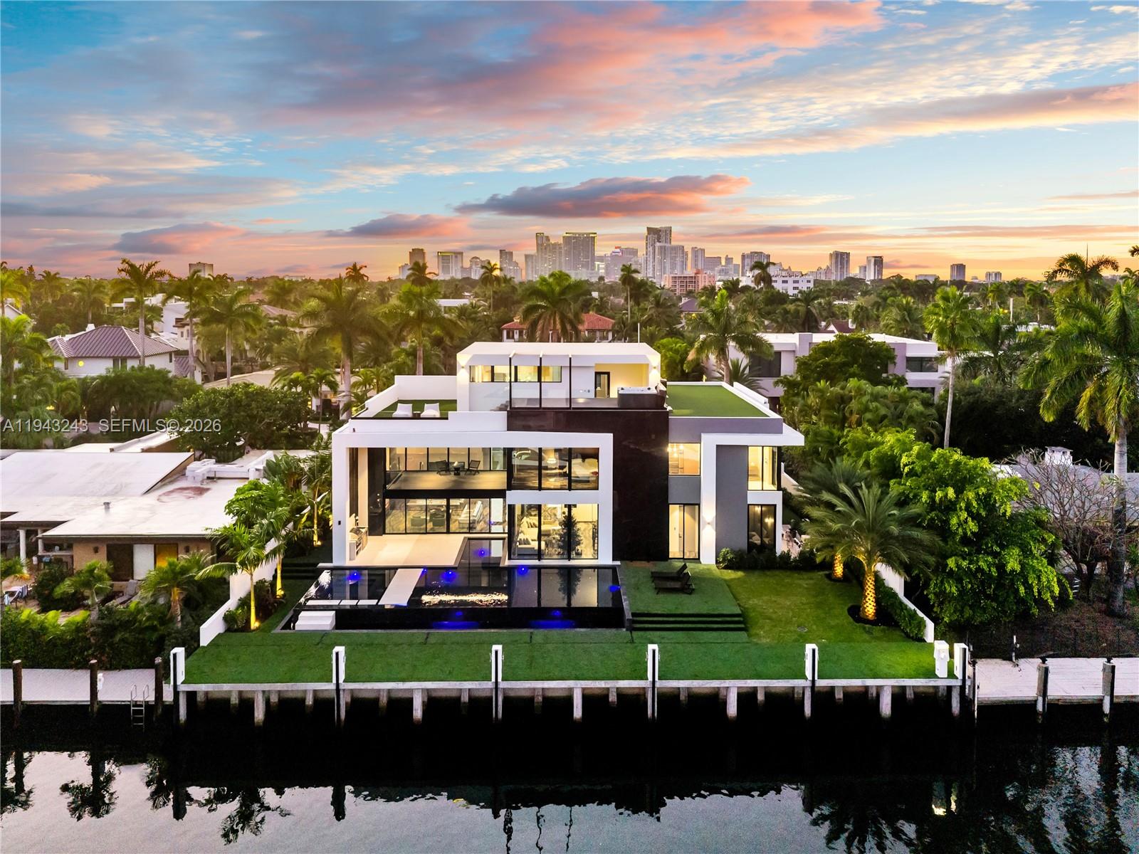 An extraordinary expression of contemporary luxury, this newly constructed Las Olas Isles estate is a rare convergence of design, craftsmanship, and waterfront prestige. The three-story residence features 100 feet of deep-water frontage, bespoke European craftsmanship, five bedrooms, and a one-of-a-kind expansive home office.Over $1.4M in Italian millwork by renowned Italian manufacturer Febal Casa defines the interiors, where nearly every surface is finished in custom upholstered wall panels. Immaculate architectural detailing creates a richly layered, refined, and acoustically elegant environment; with the exception of the ceilings, less than 1% of the home utilizes drywall—an extraordinary level of finish rarely seen.Offered fully furnished and turnkey, the home showcases a globally curated collection of custom and designer furnishings, many created exclusively for this residence. Book-matched porcelain flooring imported from Spain flows throughout, complementing the chef’s kitchen outfitted with Miele appliances and integrated Italian sinks. Lutron home automation, Delta lighting inside and out, Grohe and Kohler fixtures, and a custom-furnished elevator deliver seamless, elevated living.Additional highlights include a full private theater with custom paneling, floor-to-ceiling doors with concealed hinges, a rooftop jacuzzi and entertainment area, and a brand-new concrete seawall and dock—ideal for serious yachting, framed by downtown sunset views.