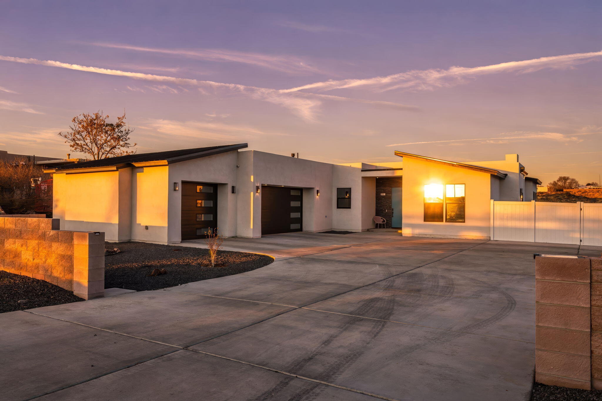 A striking custom-built contemporary residence set on an expansive .56-acre parcel in the heart of Rio Rancho. Spanning 2,727sf, this refined home offers 4 generously appointed bedrooms & 3 bathrooms. An open, light-filled floorplan hosts a spacious living area accented by custom built-in cabinetry and a fireplace. Chef's kitchen anchors the home with sleek white cabinetry, quartz countertops, and high-end appliances, complemented by a generous island with seating and a large walk-in pantry. The owner's suite is a serene retreat featuring windows that frame stunning views, private outdoor access, and a spa-inspired bath. Private outdoor living includes a heated saltwater pool, hot tub10-ft gated access, RV cleanouts, sports court, covered patio, and stunning mountain views. Owned Solar!