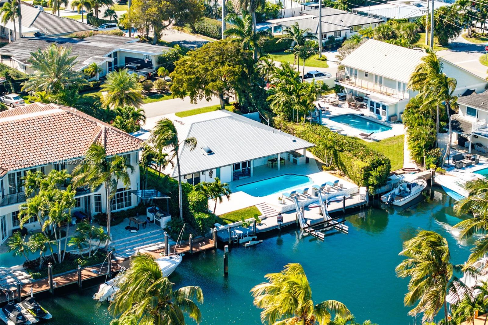 Located in the highly desirable Lake Placid enclave of Lighthouse Point, this refined waterfront residence offers approximately 75± feet of deepwater frontage, just minutes from the Intracoastal Waterway and Hillsboro Inlet.  The home presents a modern, open-concept layout with porcelain flooring throughout and significant upgrades, including all-new PVC plumbing with cast iron fully removed, a new Electrical Panel, Metal Roof and all Impact Windows & Doors. The Chef’s Kitchen is appointed with Italian cabinetry, quartz countertops, and Viking appliances with a gas stove. Outdoor living is thoughtfully designed with a covered lanai featuring a summer kitchen, marine-grade grill, marble pavers, overlooking a heated pool with new Diamond Brite finish, new skimmer, and updated equipment. Additional highlights include automated window treatments, upgraded AV with Sonos system throughout, fiber internet and an epoxy-finished garage with custom built-in cabinetry. Boating features include a TREX DOCK, 20,000 lb BOAT LIFT with underwater lighting, and a professionally maintained seawall. Boat lift fully serviced and maintained. An exceptional waterfront property offering premier boating access on a protected deep water canal with no through traffic.