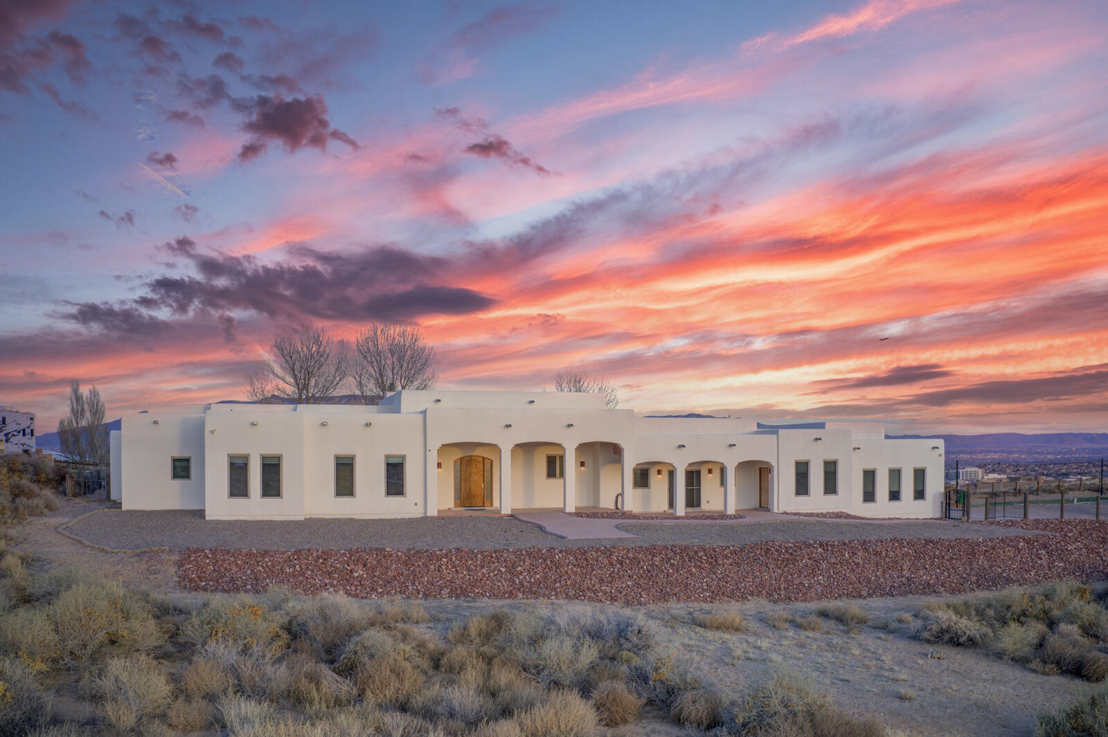 Custom single-story luxury home in Rio Rancho Estates on a private 2-acre gated lot. Built in 2008, this 4,676 SF residence offers 4 bedrooms & 5 baths with soaring 14' ceilings, abundant skylights & natural light. Chef's kitchen features custom knotty-alder cabinetry, Jenn-Air stainless appliances, double ovens, gas cooktop, expansive granite countertops. Owner's suite includes a sitting area with fireplace, spa bath, custom walk-in closet & direct lap pool access. Separate media room w/ kitchenette, soundproofing, & half bath. Indoor pool room w/sauna & dedicated HVAC. Radiant heated floors -5 zones, solar (10KW), 3 AC units, oversized 3-car garage, RV parking, outdoor kitchen, kiva fireplace, observation deck, & breathtaking mountain, city light, balloon & sunset views. ADA Compliant.