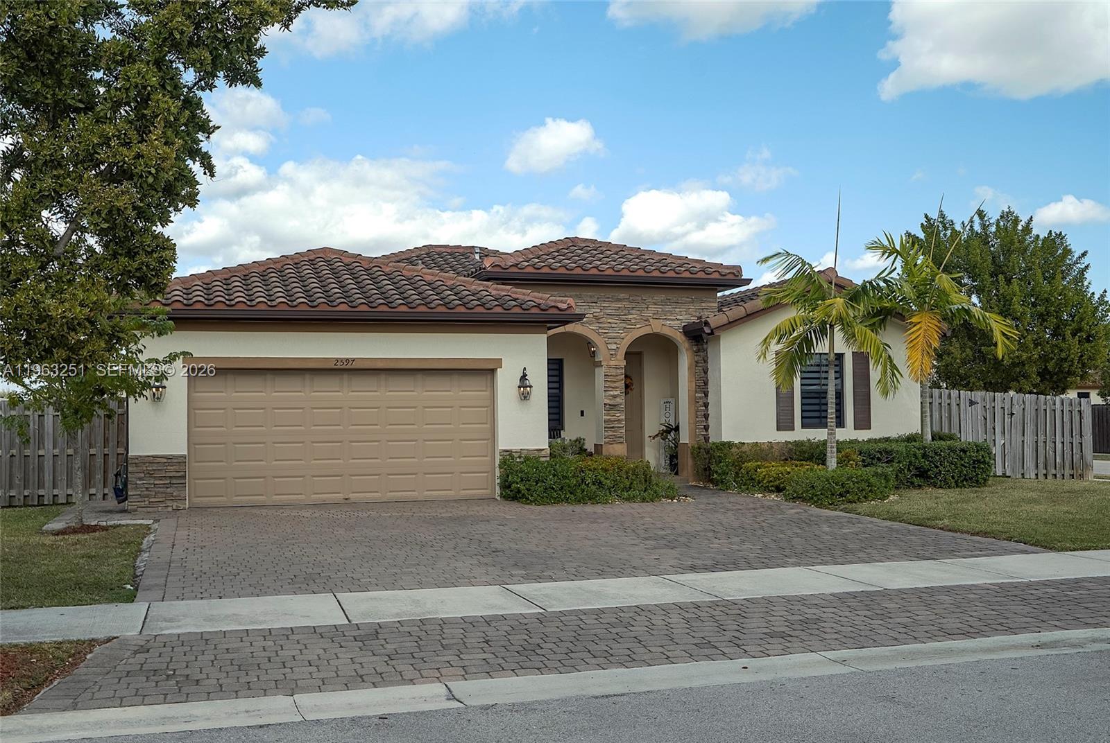 Welcome to your private corner lot retreat in a gated Homestead community, just minutes from shopping, dining, and major highways. Enjoy the convenience of HOA maintained front landscaping and access to resort style amenities including a pool, gym, clubhouse, and playground.Designed for both comfort and entertaining, the backyard showcases a heated saltwater pool with custom multi-color lighting perfect for year round swimming, relaxing evenings, or unforgettable gatherings. The fully fenced premium lot and extended driveway provide added privacy and functionality.Inside, the upgraded kitchen features quartz waterfall countertops and a designer backsplash, creating a sleek, modern centerpiece. Dimmable lighting throughout, zebra blinds, and blackout shades in the primary suite add warmth and flexibility to every space. Custom closet systems offer thoughtful organization.Smart home enhancements include a centralized WiFi hub, smart thermostat, Ring doorbell, keyless entry, smart garage control, EV-ready 240V hookup, and generator connection for added peace of mind. Hurricane shutters included. A seamless blend of style, technology, and everyday luxury.