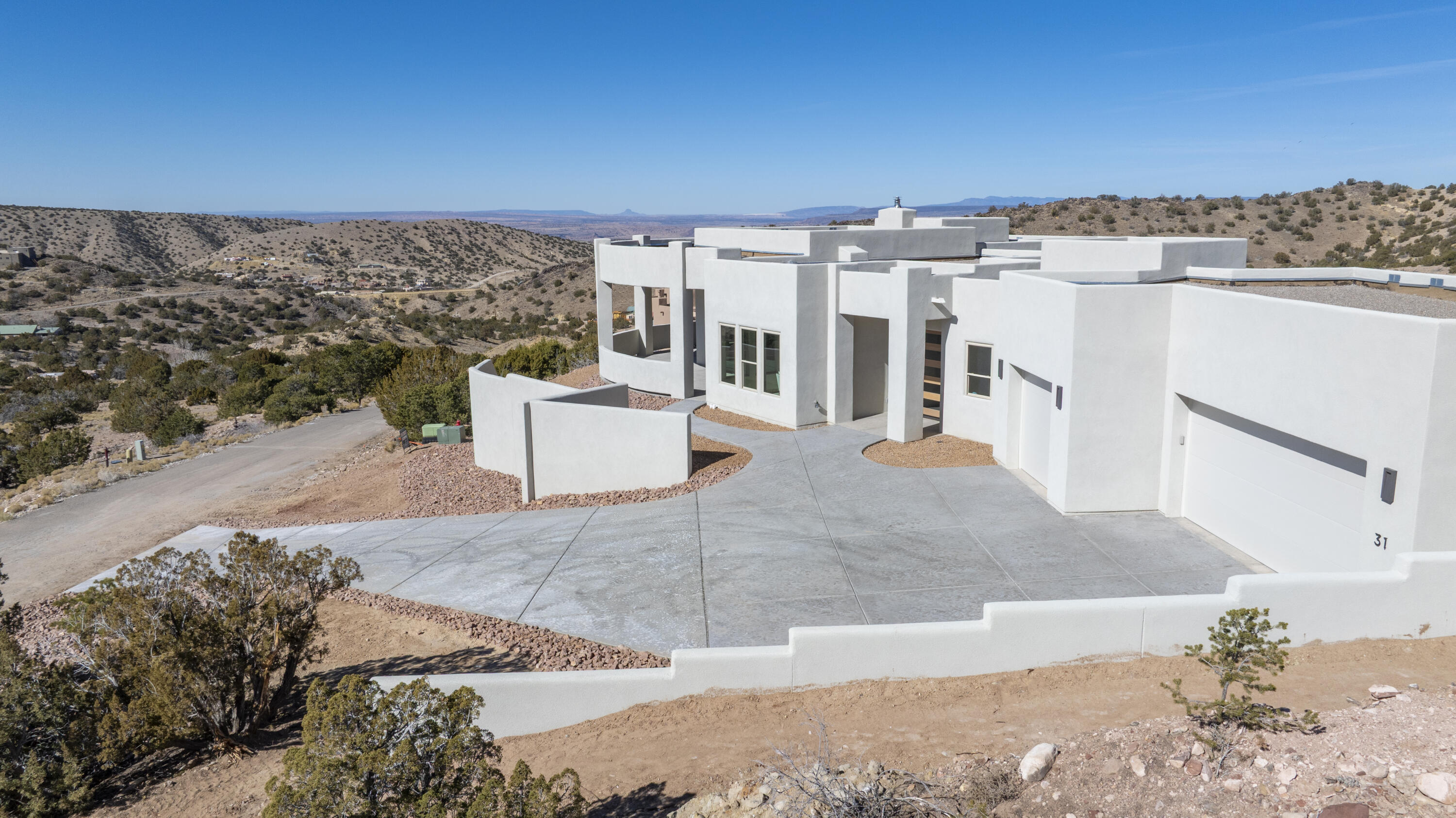 Ultimate view home by Enchanted Spaces, Placitas' premier Parade of Homes award-winning builder. This modern Southwest residence, on the highest lot in the Los Pastores Subdivision, captures sweeping views of the Sandia Mountains, Jemez mesas, and Cabezon. The efficient floor plan offers a spacious great room plus a separate flex space. The open kitchen features granite countertops, storage, a large island with seating, stainless steel appliances, a 6-burner range, and built-in wall oven. A striking fireplace anchors the living area and opens to a covered patio for seamless indoor-outdoor living.  The light-filled primary suite offers patio access, a soaking tub, dual-head shower, and custom tile. Additional highlights include a dedicated office and custom details throughout.