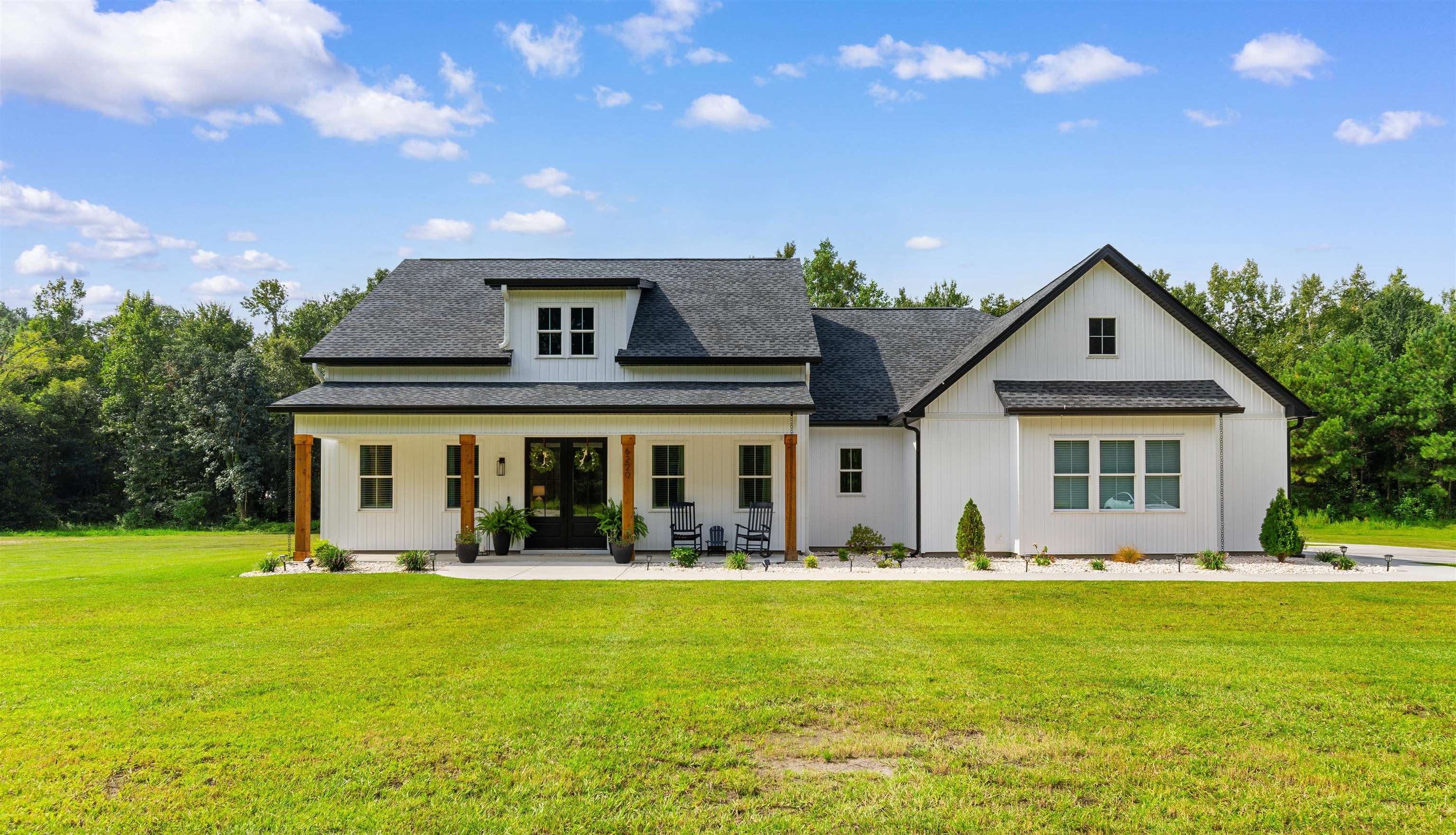 Welcome to this custom built modern farmhouse where thoughtful craftsmanship and intentional design come together on 1.64 acres with no HOA! Framed by a mature tree line, the property offers space to expand, entertain, or create the outdoor setting you’ve always wanted! An oversized two car garage plus a 24 x 30 detached garage with concrete flooring provide exceptional flexibility for vehicles, storage, equipment, or workshop space. A long private driveway creates a welcoming approach and sets the home back beautifully from the road. Inside, the thoughtfully designed 3 bedroom, 2.5 bath split floor plan blends functionality with elevated style! The open concept living room features cathedral ceilings, a cozy fireplace, and custom wood built ins, while the formal dining room offers a beautiful setting for gatherings and entertaining. The kitchen is a true centerpiece, showcasing two tone cabinetry with classic white perimeter cabinets and a warm wood tone center island, quartz countertops, white tile backsplash, stainless steel appliances, and a spacious pantry with custom wood shelving. Abundant cabinetry and expansive counter space make it as practical as it is stunning! The private primary suite occupies its own wing, offering a spa inspired bath with double vanity, modern soaking tub, oversized tiled shower with waterfall and wall mounted fixtures, and a boutique style custom closet complete with extensive shoe storage. The closet connects directly to a spacious laundry room featuring cabinetry, sink, and folding counter for added convenience. Bedrooms two and three are positioned on the opposite side of the home and share a beautifully designed hall bath featuring dual sinks and a private shower and tub combination, offering a classic twist on a Jack and Jill layout while maintaining privacy and usability. Outdoor living is equally inviting with a rocking chair front porch and an extended screened back porch with dual ceiling fans, thoughtfully designed for comfortable everyday living and relaxed evenings at home. With 1.64 acres to call your own, there is endless potential to create your ideal outdoor retreat, whether adding a pool, outdoor kitchen, garden, or simply enjoying the open space. Located just 10 minutes from historic downtown Conway and approximately 25 minutes to Myrtle Beach via Highway 22, this property delivers the perfect balance of quiet country living and coastal convenience.