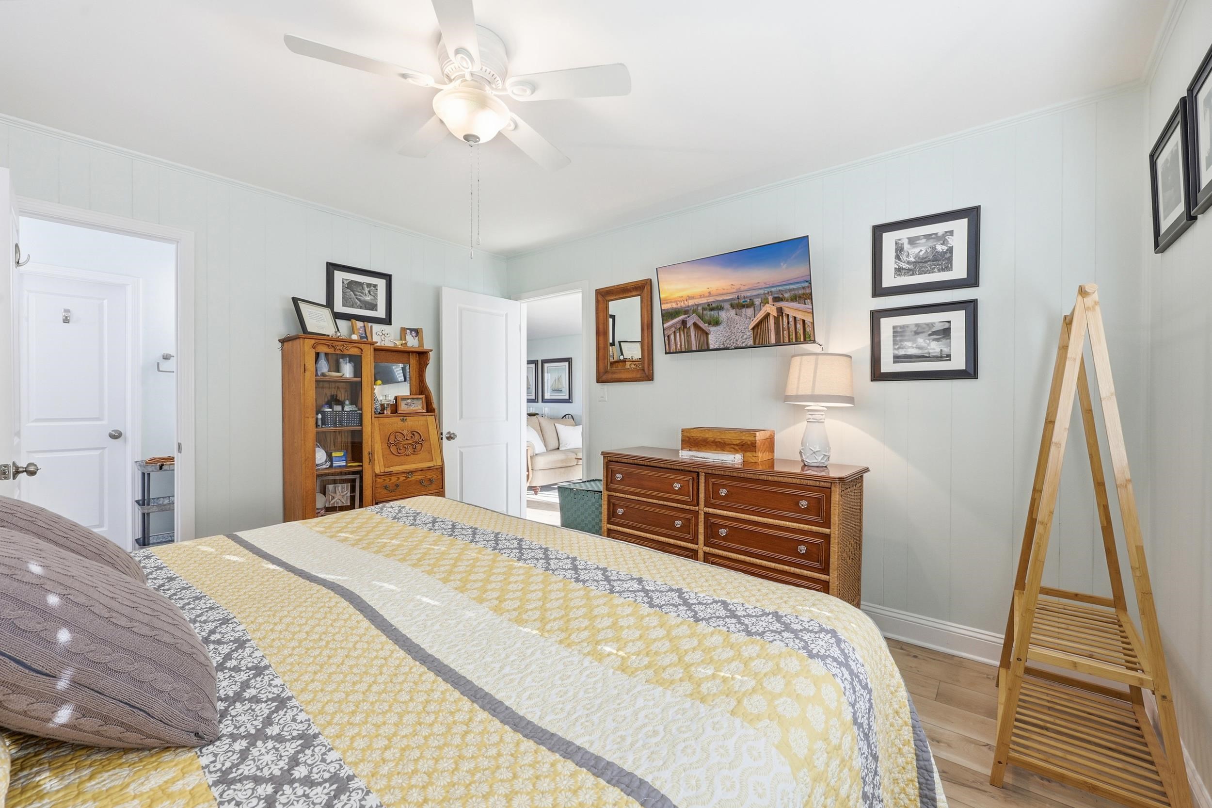 Bedroom with light wood-style flooring, a ceiling fan, and wood walls