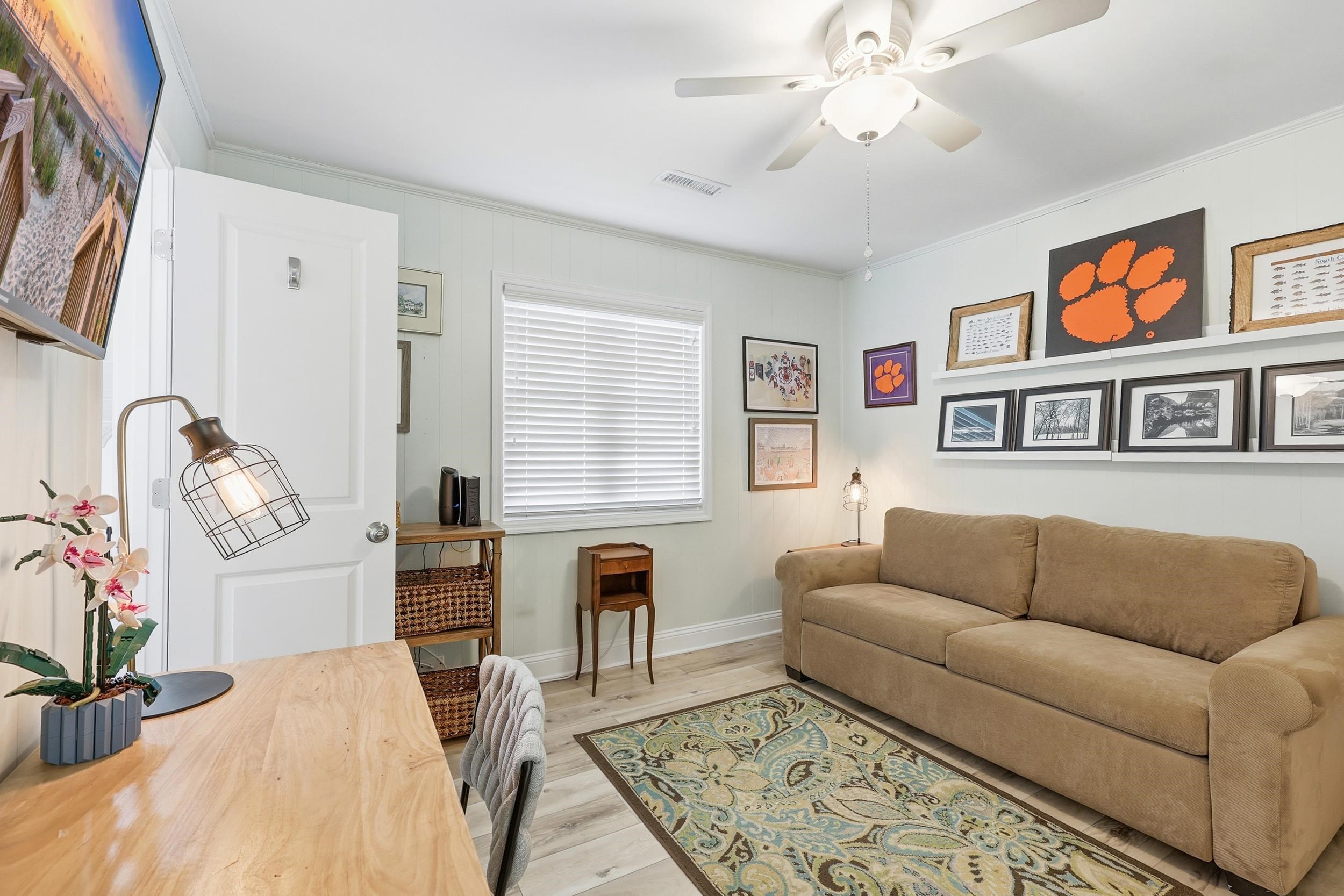 Living area with crown molding, wood finished floors, and a ceiling fan