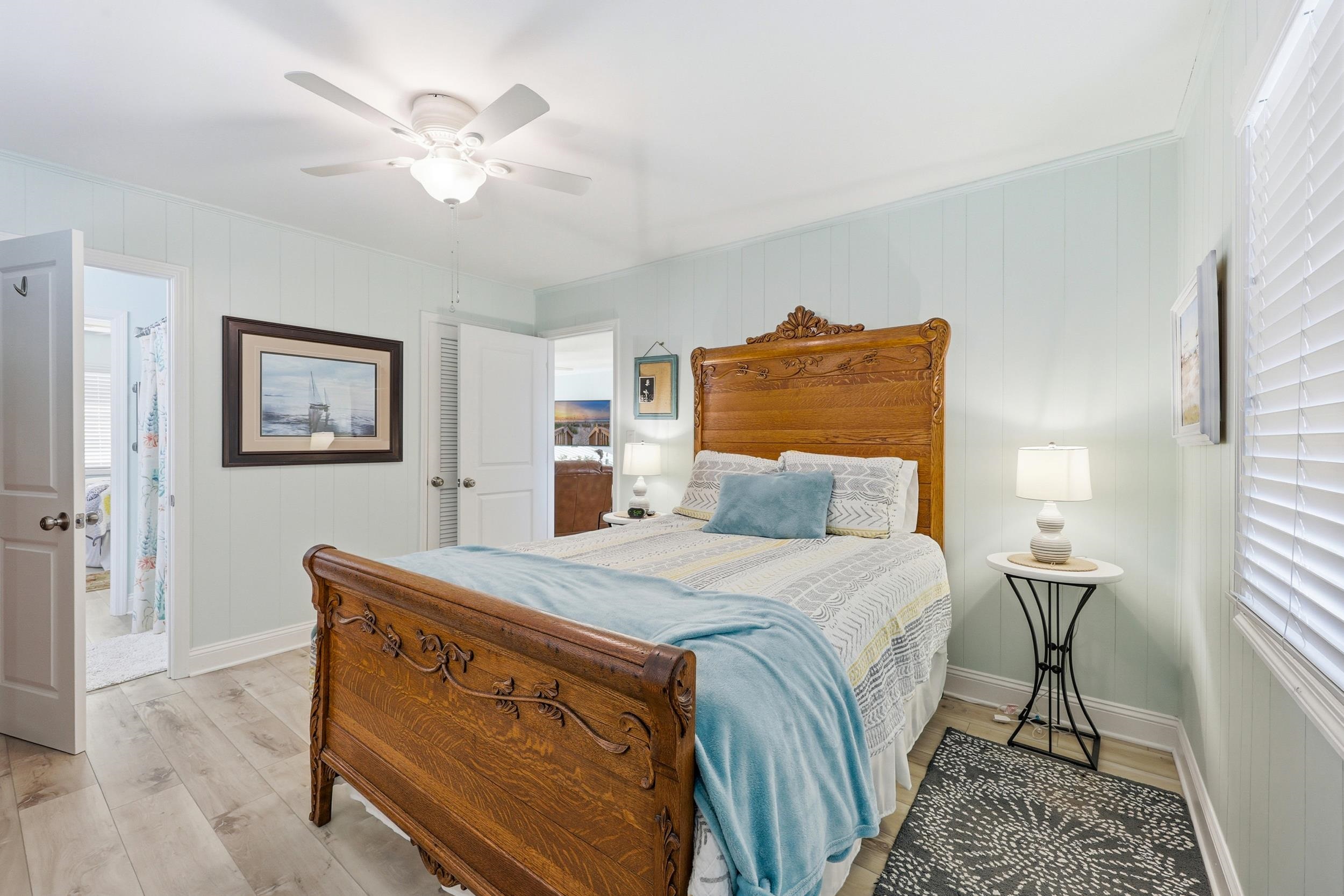 Bedroom with light wood finished floors, ceiling fan, wood walls, and a closet