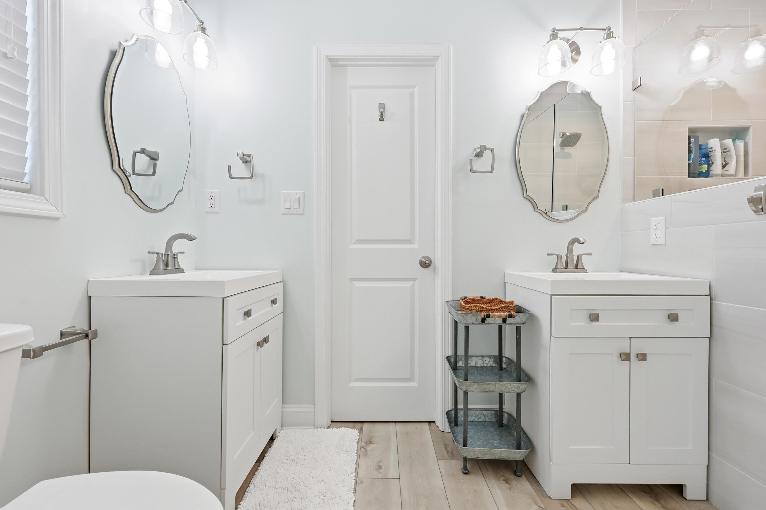 Bathroom with two vanities and light wood finished floors