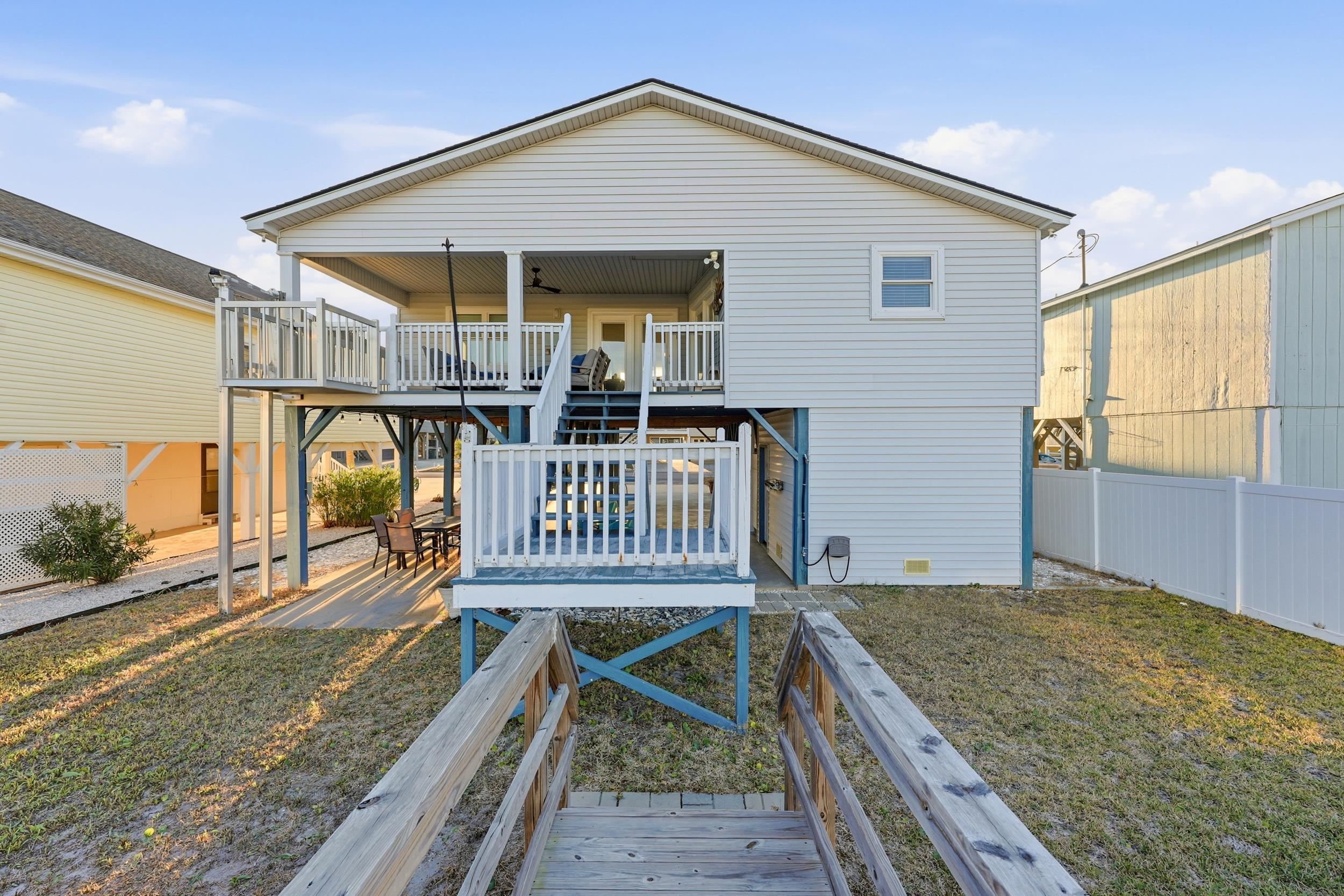 Back of house with stairway, a wooden deck, and a patio