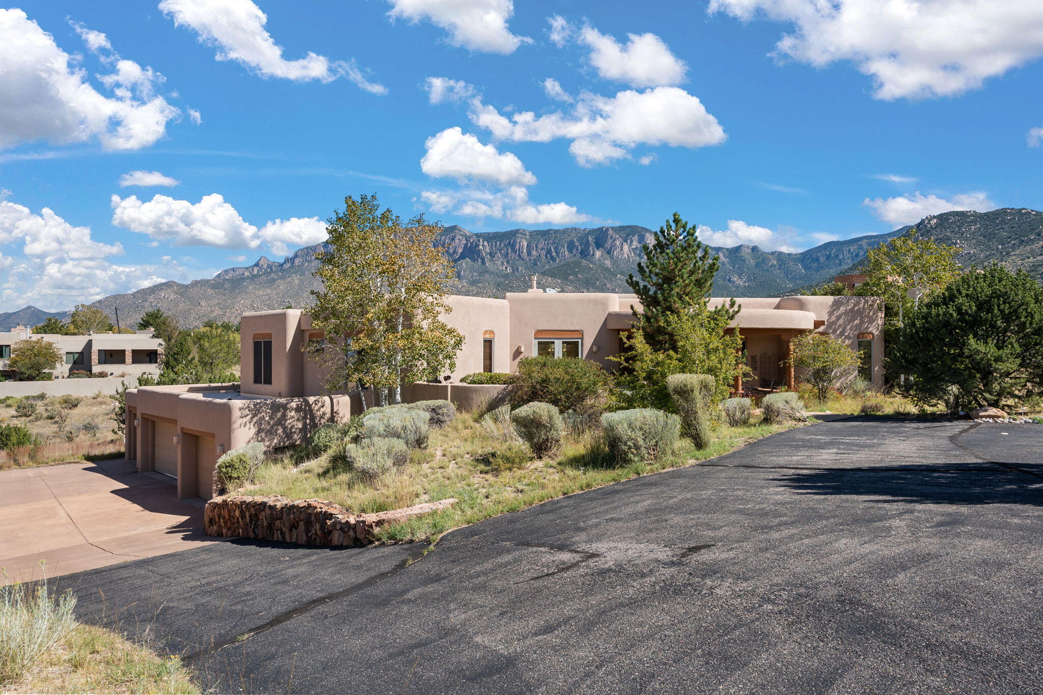 Experience elevated Southwest living in this custom Pueblo-style estate in High Desert. Situated on a private 0.94-acre lot, this 4,224 sq ft home offers 3 bedrooms, 3 baths, and an expansive open floor plan with soaring ceilings, exposed vigas, and hand-troweled plaster walls. Enjoy panoramic Sandia Mountain and city light views from multiple patios. Designed for both luxury and function, features include multiple living areas, wet bar, office space, and a 5-car garage with 2 EV charging stations and owned solar panels. Outdoor amenities include a heated pool, spa, and direct access to scenic trails. A rare blend of privacy, architecture, and views in one of Albuquerque's premier communities.