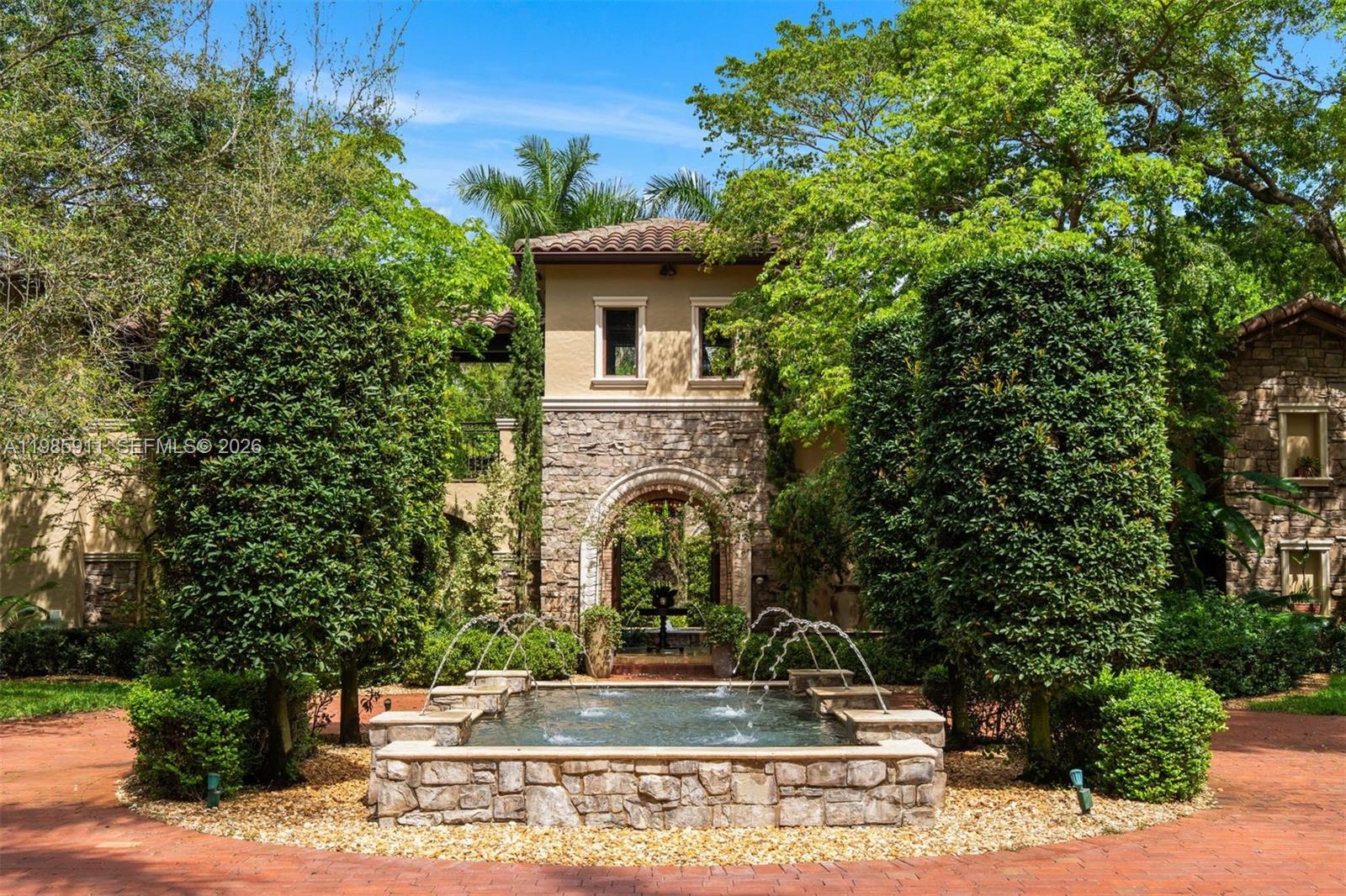 Set on a sprawling 1.12-acre lot in the heart of Pinecrest, this extraordinary grand Tuscan-inspired estate offers 6,624 SF under air and 9,771 total SF with 6 bedrooms and 8.5 bathrooms. A gated entry and sweeping palm-lined driveway lead to a private, resort-style compound defined by timeless Mediterranean architecture, a barrel tile roof, and lush, manicured grounds. The multi-structure layout surrounds a spectacular heated pool with resort-grade saltwater chlorination and spa, covered terraces and a fully equipped summer kitchen for seamless indoor-outdoor living. Interiors feature soaring ceilings, travertine, wood and stone floors, a dramatic atrium courtyard, formal living and dining rooms, and a spacious family room. The chef’s kitchen is equipped with granite countertops, custom cabinetry, Sub-Zero refrigeration, and a full Thermador appliance suite. Additional highlights include a custom bar, wine cellar, home theater, and private office. The main-level primary suite offers a sitting area and a spa-inspired bath with soaking tub, dual vanities, and walk-in closets. A separate guest residence with living area and kitchenette, plus staff quarters, provide flexibility. Modern comforts include impact windows, Control4 smart home and audio, Generac generator, mosquito system, 3-car garage, and more—delivering exceptional privacy and comfort in one of Pinecrest’s most desirable settings.