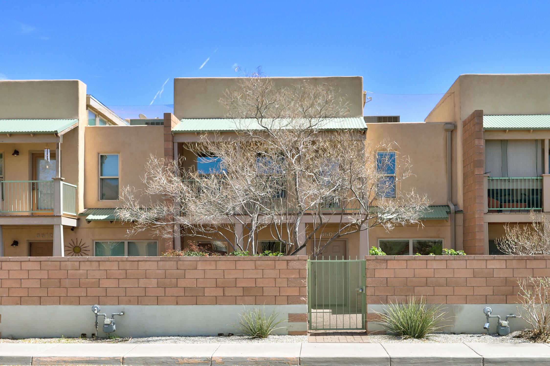 A quiet, light-filled, contemporary urban row house in the near north valley. No better value for your money. Close to the nature center, acequias, parks, bike trails, Starbucks, Co-Op; minutes from I-40 and I-25. Architect-designed floor plan with kitchen, living and primary bedroom upstairs, with 12' wood beam ceilings, clerestory windows, granite counters, upgraded cabinets, stainless appliances, wood and polished concrete floors. Landscaped courtyard, and two balconies. Flexible 3rd bedroom, office or den space. Two car garage with built-ins, and a ton of storage throughout. Newer TPO roof. Energy Star certified construction. Built-in vacuum system. Newer HVAC package unit. Truly, this house is of the highest quality, the neighbors are great, and there's even a built-in doggy door!