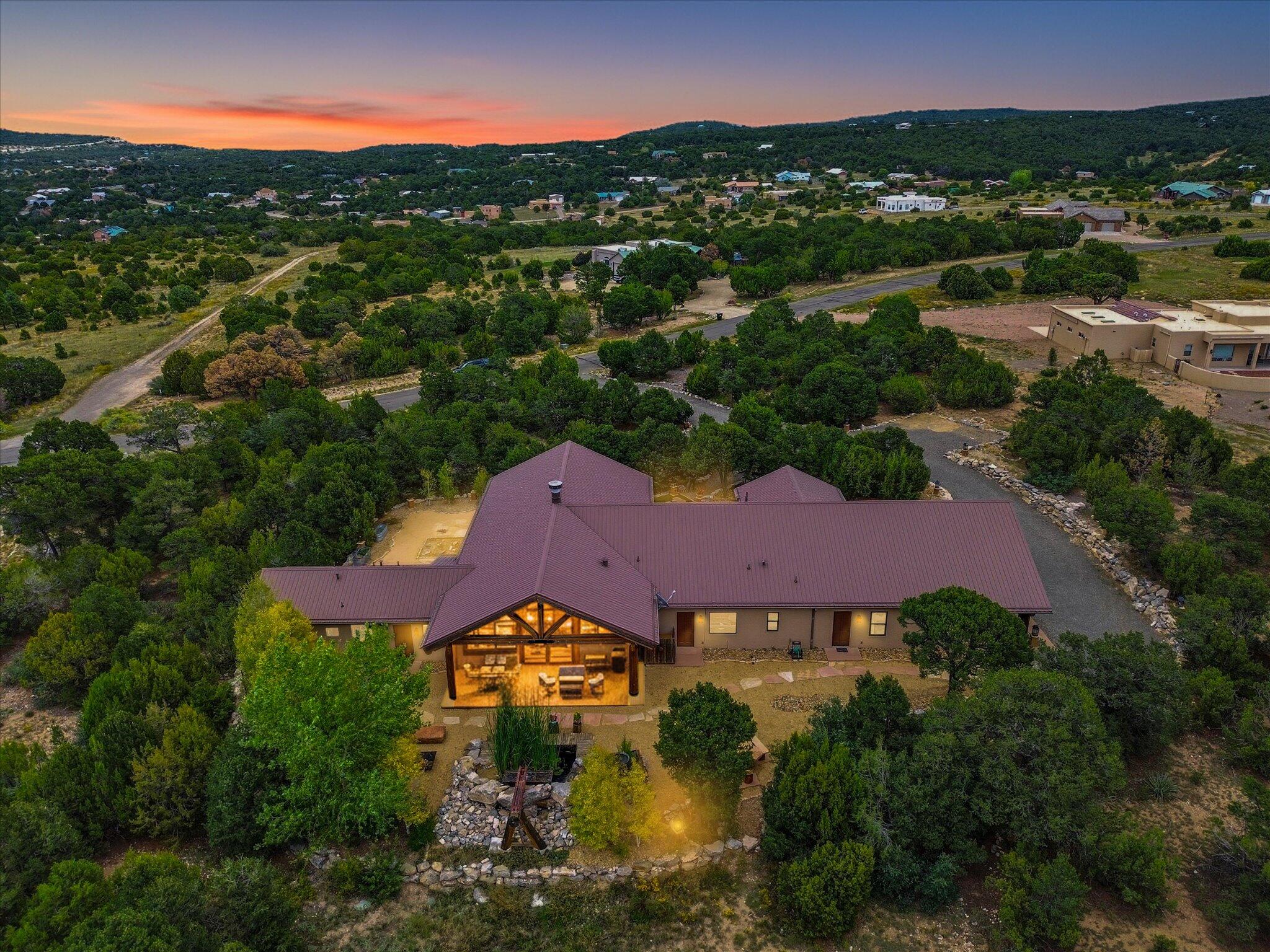 Country Lodge-Style Home in Gated Community. Casually elegant lodge-style home in a country setting, designed to highlight 4 seasons with walls of windows, 20 ft wood ceilings, and massive trusses in the great room. Two living areas are divided by a two-way stacked stone fireplace, with a striking water feature inside the front entry. Interior features include concrete radiant-heated floors, wood vigas, and a chef's kitchen with 2 ranges, dishwasher, wine cooler, built-in refrigerator, rainforest quartz island, copper hood and backsplash, and a large pantry. A built-in china hutch adds to the custom design. The main suite includes a Jacuzzi tub, fireplace, and a large walk-in closet. Additional amenities feature a 1,369 sq. ft. attached 3+ car garage/workshop.