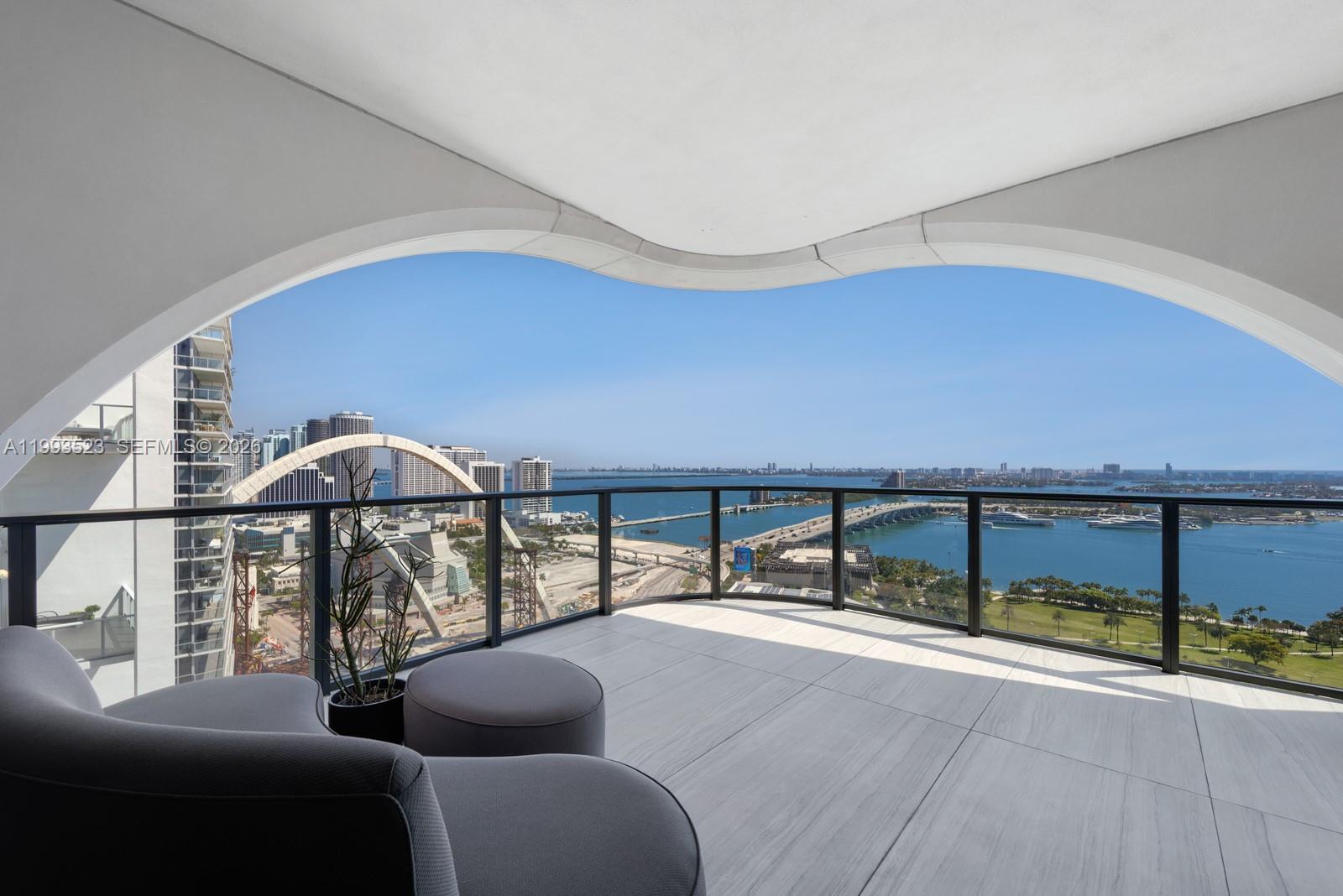 Rising above Miami's most iconic skyline, Unit 2702 at One Thousand Museum stands as a rare offering within Zaha Hadid's final architectural legacy, a 4-bedroom, 5.5-bathroom residence spanning 4,600 square feet of flawlessly curated living space. Positioned in one of the most privileged lines in the building, Unit 2702 commands breathtaking Northeast-facing direct ocean and Biscayne Bay views and Miami's most stunning sunrises.Completely reimagined from scratch by renowned architect Luciana Junqueira, every inch reflects an uncompromising commitment to luxury. Suspended plaster ceilings integrate custom lighting, a whole-home sound system, motorized shades, and concealed AC — all inspired and engineered to honor Zaha Hadid's iconic architectural language, designed and installed by AHT Global.Wallpaper Miami adorns every room, water-resistant textures in living areas, silk-infused in the powder room, and straw-woven in the master suite. Custom Madeira Bambu millwork by Oliver flows throughout, representing nearly $800,000 in customization. The living room features Roche Bobois' Bubble chair and custom Artefacto pieces atop wool and silk rugs. Two Roche Bobois statement tables and Gaggenau and Sub-Zero appliances complete the kitchen.A true trophy residence in the sky. Offered fully furnished. Living in 1000 Museum is not simply an address. It is a legacy.