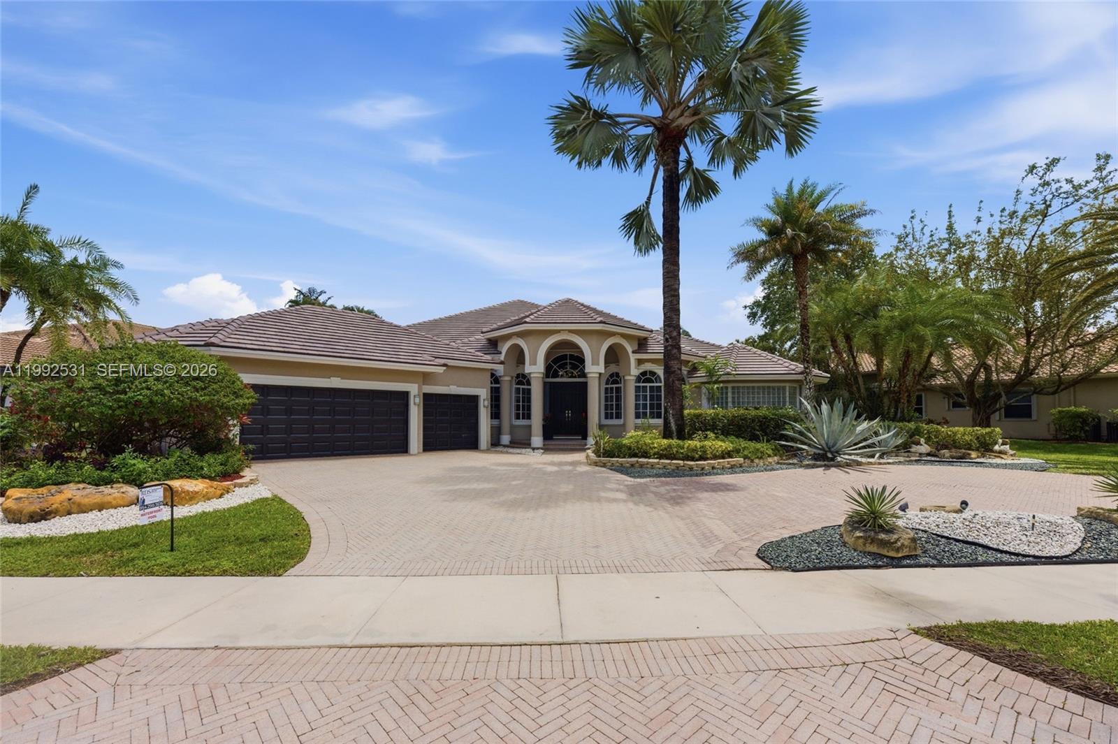 One of Weston Hills Country Club's most coveted addresses. Set on an expansive 18,265 square ft waterfront lot. Grand foyer w/ soaring ceilings, exquisite crown molding.  Brand new roof (2026) full accordion hurricane protection ensure complete peace of mind. 5 bedrooms, 4 full baths, and 2 half baths, including 4 en-suite bedrooms and a versatile office/game room. Lavish primary suite serves as a true private sanctuary, showcasing a tray ceiling and sweeping views of both the pool and the lake. The chef's kitchen is appointed with rich wood cabinetry, granite countertops, and Brand new top-of-the-line stainless steel appliances, opening seamlessly to a warm family room and a sophisticated wet bar, an ideal setting for gatherings of any scale. Refined touches are found throughout: central vacuum, a whole-home built-in speaker system (interior and exterior) powered by a Bose Music Amplifier with Bluetooth and Wi-Fi connectivity, and a covered screened patio with cool deck leading to a resort-style pool and private outdoor grill area. Lush, manicured landscaping and a striking circular brick paver driveway frame the property with timeless curb appeal, while the 3-car garage features a Tesla EV charging station. Every detail has been curated for the discerning buyer who demands luxury, comfort, and the unrivaled lifestyle that only Weston Hills Country Club can offer.