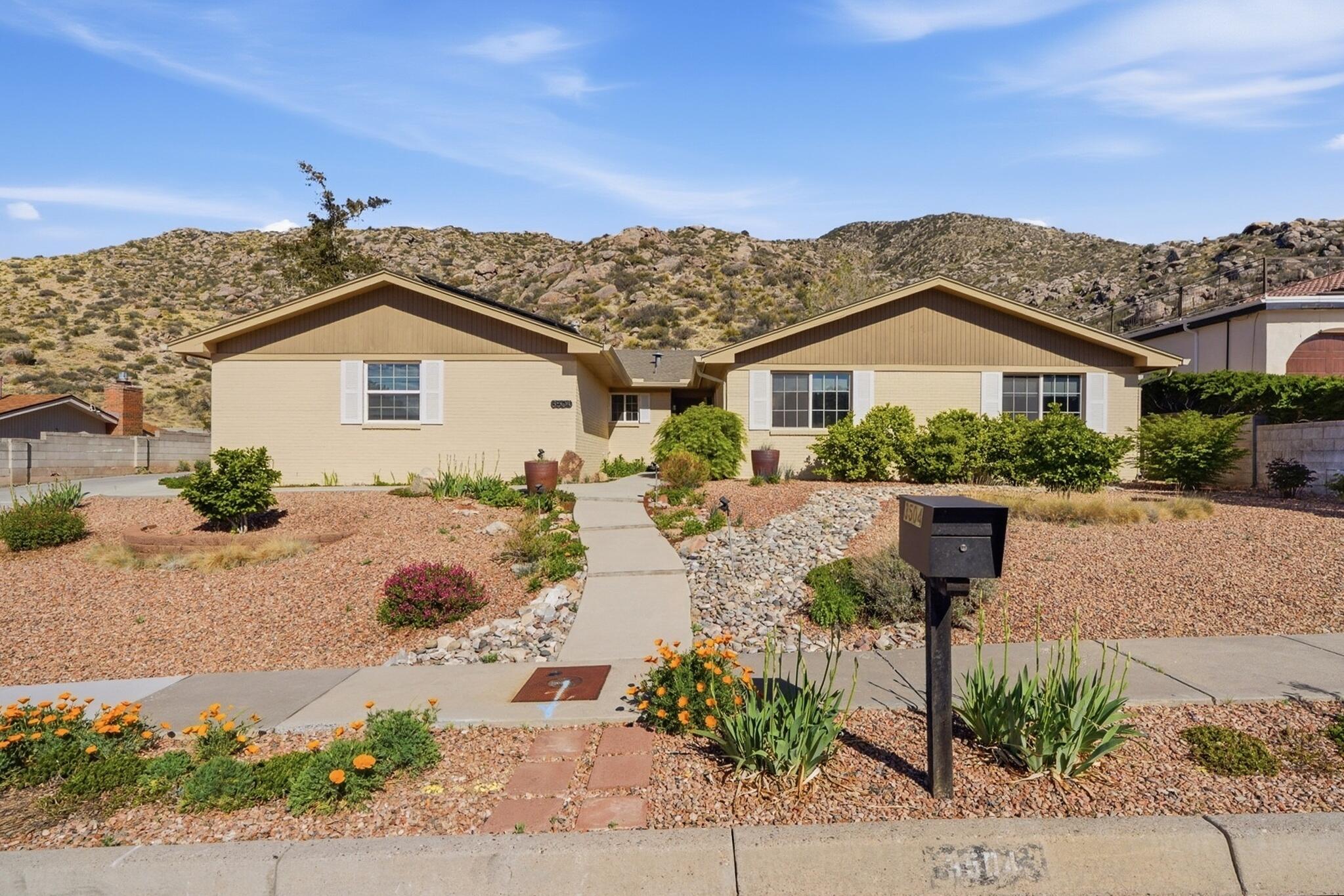 Tucked against the foothills, this beautifully maintained 4-bedroom, 2.5-bath home brings the Sandias right to your backyard. Step through large sliders to two inviting patios, a deck, hot tub, and firepit--perfect for relaxing or entertaining. A private back gate opens directly to a scenic walking trail. The easy-care yard is lush with flowers, shrubs, and roses on drip irrigation. Inside, enjoy reverse osmosis, custom blinds, and elegant drapes. Outdoors you'll find extra parking on the side of the home. Owned solar keeps energy costs low--just $12/month to PNM. A rare blend of comfort, efficiency, and breathtaking natural beauty.