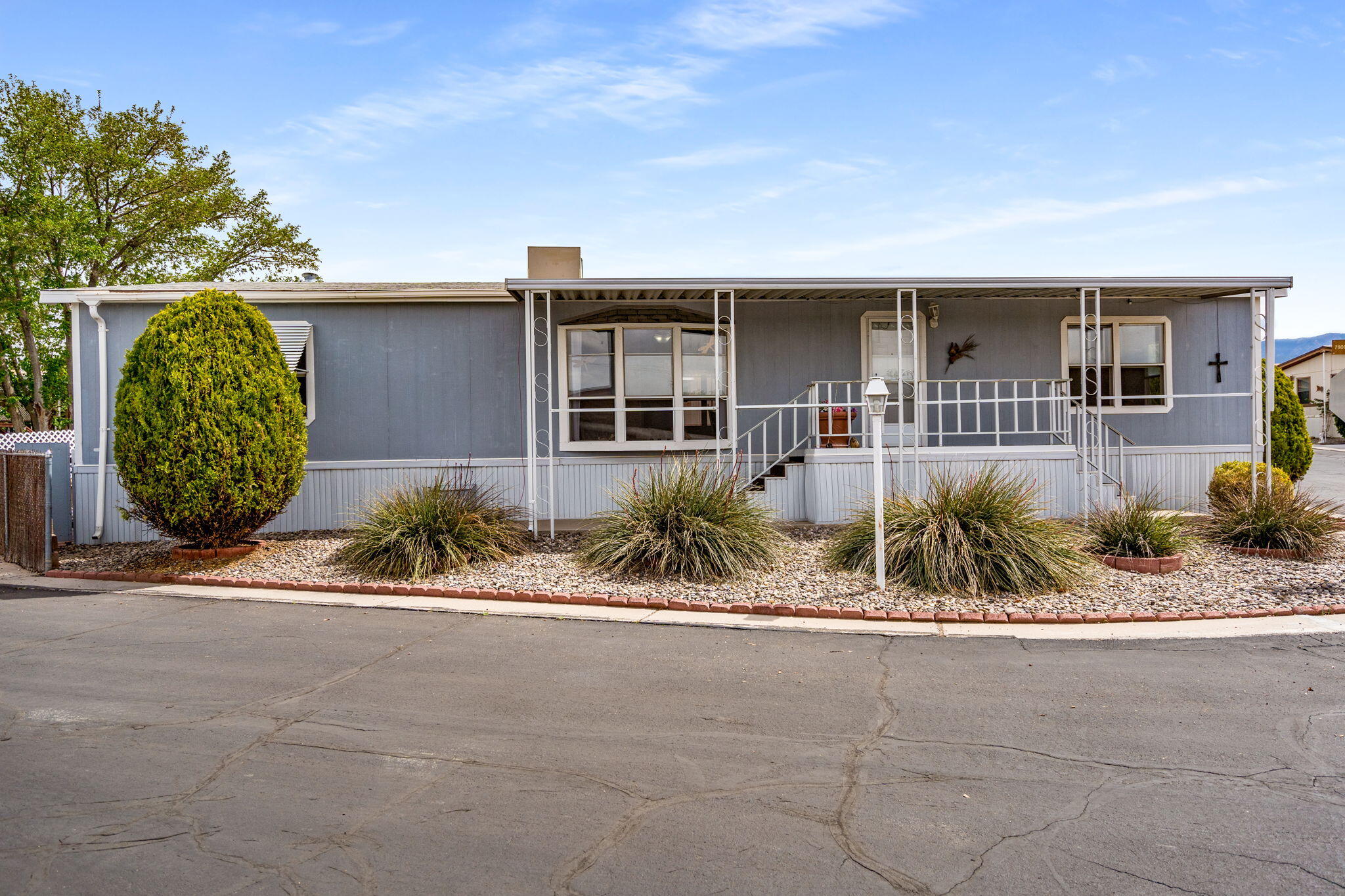 Enjoy this spacious double-wide home in the gated 55+ North Hills Mobile Home Park in NE Albuquerque. This large home features 3 bedrooms and 2 bathrooms, an updated kitchen, and is located on a corner lot. Relax on the front or back deck.  Two sheds provide plenty of outdoor storage.  Enjoy the convenience of a central location close to shopping, dining, recreation, and healthcare. The community boasts amenities like a clubhouse, swimming pool, and tennis courts - ideal for socializing and enjoying the North Hills lifestyle.