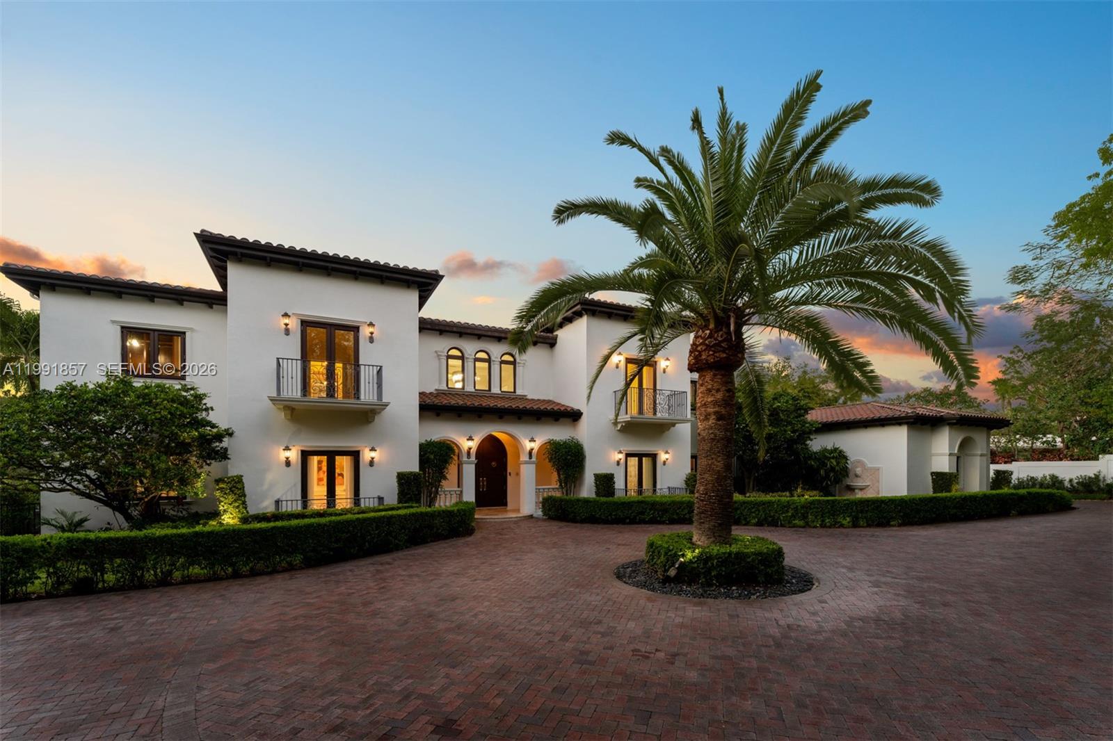 Timeless Mediterranean estate set on nearly an acre, offering 9 bedrooms, 8 full baths and 1 half bath across a well-designed layout. A welcoming foyer introduces formal and casual living spaces, highlighted by a spiral staircase leading to second-floor balconies and a seamless indoor-outdoor flow. The home includes a wine cellar,and covered terraces suited for entertaining. The primary suite features dual walk-in closets and a private setting. Outdoors, a pool with tanning ledge, jacuzzi, and fully equipped summer kitchen create a comfortable retreat. A fireplace, separate guest house, and 4-car garage complete this well-appointed residence.