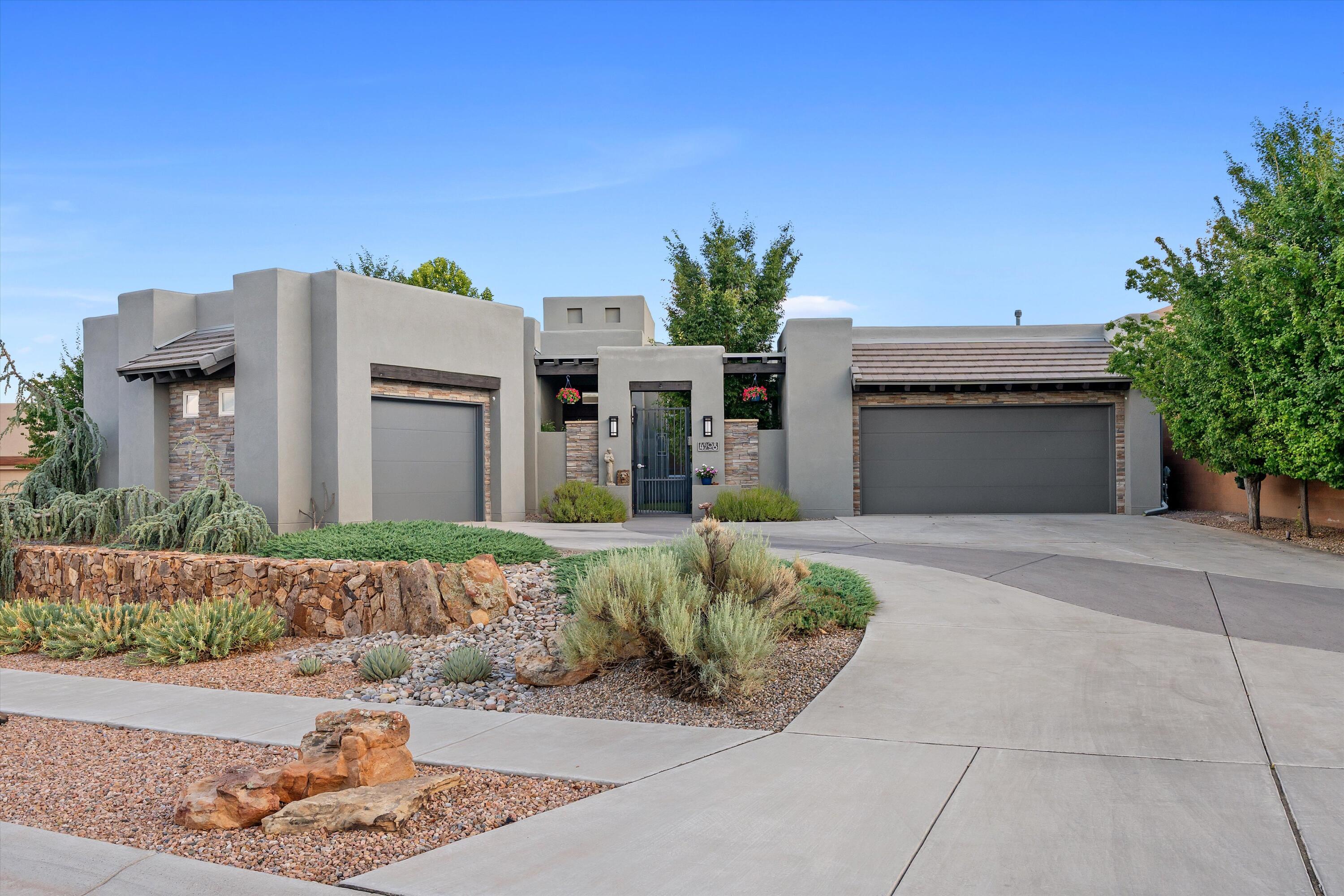 Set within the gated El Bosque community near Albuquerque's Rio Grande bosque, this custom single-story Scott Patrick home offers something increasingly difficult to find: refined contemporary design, generous indoor-outdoor living, and direct community access to the Bosque Trail--all in one thoughtfully planned property.The experience begins before you step inside. A private enclosed courtyard, soothing water feature, and beveled-glass entry create a welcoming transition into a gallery-inspired foyer with soaring ceilings and expansive walls designed to showcase art. From there, the home opens into light-filled living spaces that balance architectural presence with an inviting, comfortable feel.At the center of the 3,201-square-foot floor plan is a spacious great room with a custom gas fireplace and a natural connection to the kitchen, dining areas, and covered outdoor living space. The kitchen is designed for both everyday use and entertaining, with an oversized island, four-burner gas range, double ovens, convection cooking, beverage refrigerator, generous cabinetry, and pantry storage. Whether preparing a quiet dinner or hosting a full house, the layout keeps everyone connected without crowding the workspace.The flexible single-level design includes a primary suite, a second bedroom, a third room that can function as either a bedroom or office, and a fourth room currently designed as a dedicated home theater. The primary suite offers a spacious bedroom, dual vanities, a garden tub, separate shower, private water closet, and walk-in closet. A formal dining room, wine room, skylights, high ceilings, and thoughtfully placed display areas add character and purpose throughout the home.Step outside and the setting becomes part of the architecture. The expansive covered patio looks across a professionally designed backyard with low-maintenance SynLawn, xeric landscaping, drip irrigation, and a contoured putting green. Open space behind the property creates a peaceful Bosque backdrop, while Albuquerque's hot air balloons often drift into view overhead. Through the community, residents have access to the Bosque Trail, making it easy to enjoy walking, cycling, and the natural landscape along the Rio Grande.The features buyers often hope to add later are already here: owned solar, upgraded insulated windows, refrigerated air, whole-house audio, central vacuum, owned water softener, recirculating hot water, security system, and a finished three-car garage. These improvements quietly support comfort, efficiency, storage, and day-to-day convenience without distracting from the home's architectural design.Built in 2014 on approximately one-third of an acre, 4908 Camino Valle Trail NW is more than a collection of impressive features. It is a home created for displaying art, sharing meals, entertaining friends, enjoying the outdoors, and experiencing one of Albuquerque's most recognizable natural settings just beyond the backyard.