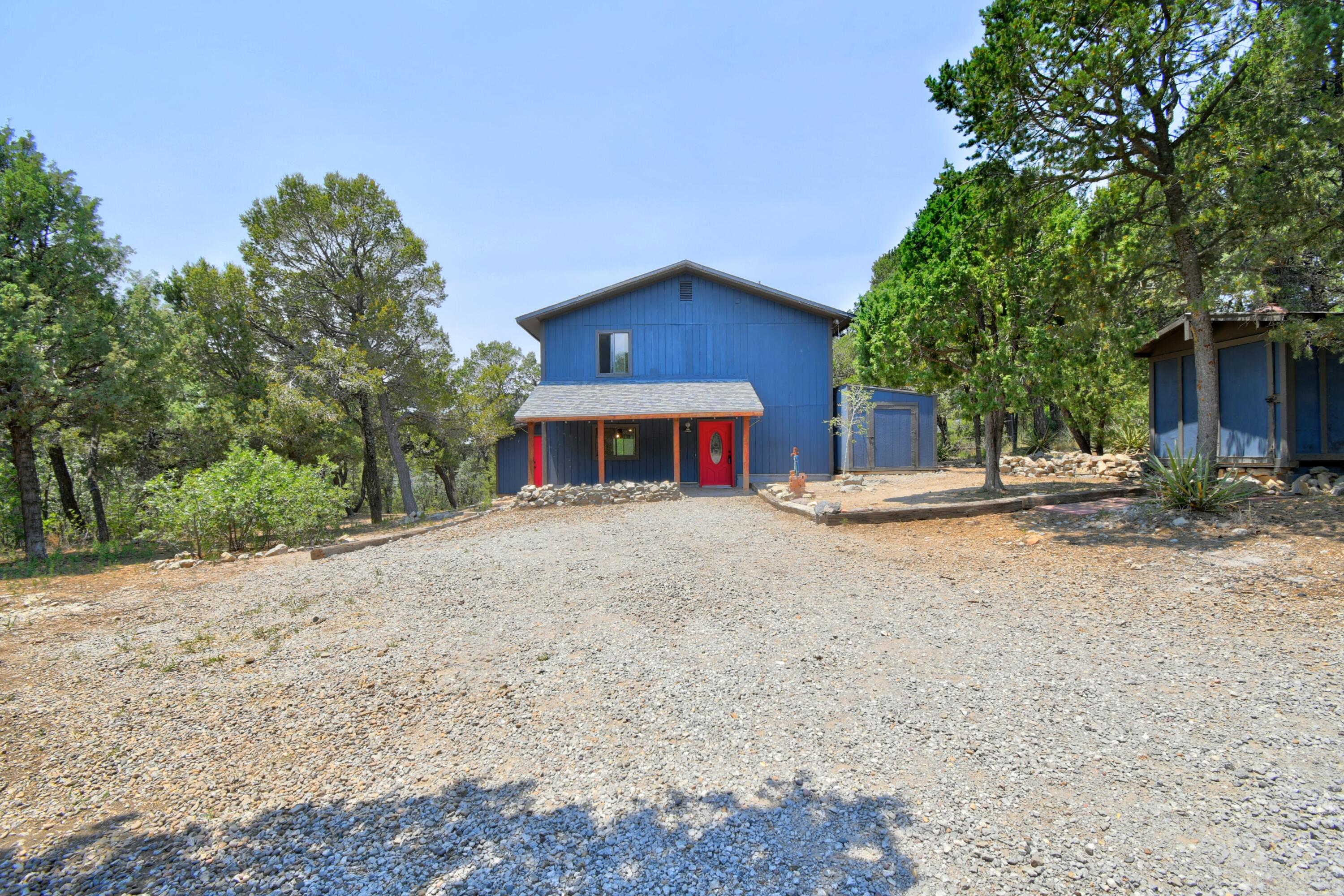 Step from your backyard into 1,633,783 acres of the Cibola National Forest! This mountain retreat offers the perfect balance of privacy and convenience, located just 20 minutes from Tramway while enjoying the benefits of a shared water system. The open floor plan features two spacious living areas, a sunken living room with soaring ceilings, a cozy pellet stove, and a bright sunroom with heat recovery fans, perfect for year-round gardening. The updated kitchen boasts quartz countertops, a stunning backsplash, a center island, and abundant cabinetry. Additional highlights include an adobe Trombe wall, tranquil pine surroundings, two storage sheds, a fenced and gated yard, and a dog run. With direct access to the Cibola National Forest, this is a true mountain retreat where adventure begins
