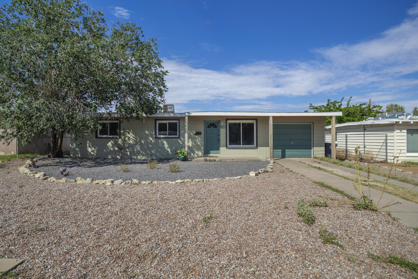 Affordable Bellamah home in Mesa Village just east of Uptown! Beautiful beamed tongue-and-groove ceilings are found throughout, along with tile floors (no carpet). Covered front porch, living room, extended dining room, and kitchen with gas range/oven and plentiful cabinets. Butcher block, granite, and laminate countertops offer a mix of colors and textures. Three bedrooms and one full bath. Laundry room with both electric and gas dryer hook-ups. One car garage. Upgraded electrical w/ mini-splits for heating/cooling. French doors open to HUGE backyard w/ storage building. Easy-care xeriscape/gravel landscape in front; the backyard awaits your special touches. Located in Sandia HS district- and Grant Middle School Park is just blocks away. Convenient access to I-40 & KAFB via Wyoming Blvd.