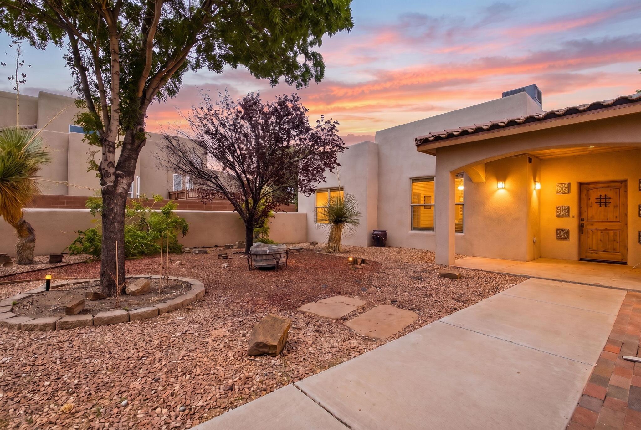 Welcome to a lovely custom home in Enchanted Hills, where sweeping views of the Sandia Mountains create a beautiful backdrop for everyday living. Designed with comfort and functionality in mind, the home offers a spacious open living area with viga beams and a formal dining space, perfect for  gatherings and entertaining.The nicely appointed kitchen and adjoining breakfast area open to the living room with a convenient breakfast bar, creating a warm and connected central living space. The thoughtfully designed floor plan provides wonderful separation of bedrooms, with the private primary suite and its full ensuite bath located on the East side of the home, while two additional guest bedrooms and a full bath are situated on the West side. The home offers radiant in floor heat, refrigerated cooling, and owned solar panels.Step outside to the covered rear portal and take in the incredible mountain views on this spacious .50 acre lot. The property also offers exceptional versatility with an attached two-car garage, as well as an additional third garage, carport, and a separate shed or studio space providing plenty of room for vehicles, hobbies, storage, or your creative pursuits. With its inviting layout, generous outdoor space, and stunning mountain views, this Enchanted Hills home offers a wonderful place to relax, entertain, and enjoy the beauty of Northern New Mexico.