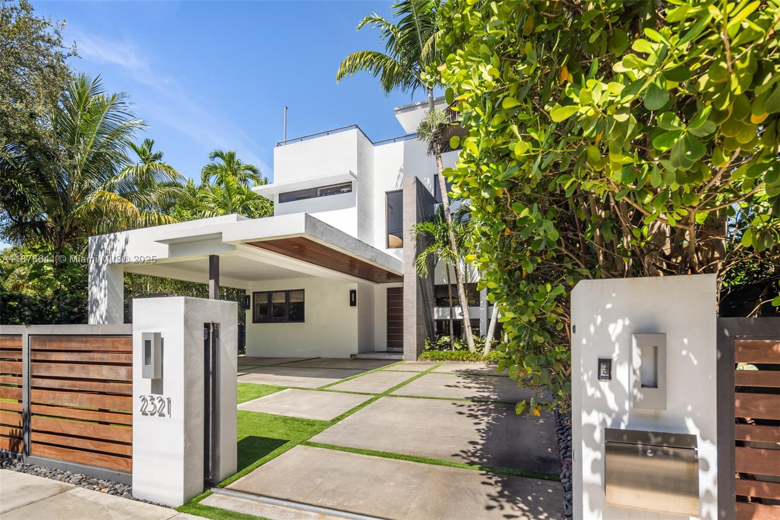 Behind a private gated entry, this tropical modern residence in North Coconut Grove blends striking design with serene surroundings. Set on a quiet, tree-canopied street near bayfront parks and marinas, the home features soaring ceilings, stone and wood floors, custom built-ins, and a chef’s kitchen with Italian cabinetry and SubZero/Wolf appliances. The primary suite offers a spa-like bath with soaking tub and glass rain shower. A floating staircase, elevator, impact glass, and 48kw generator enhance comfort and security. Outdoor living shines with a lush pool, covered terrace, and rooftop deck showcasing panoramic Grove views.