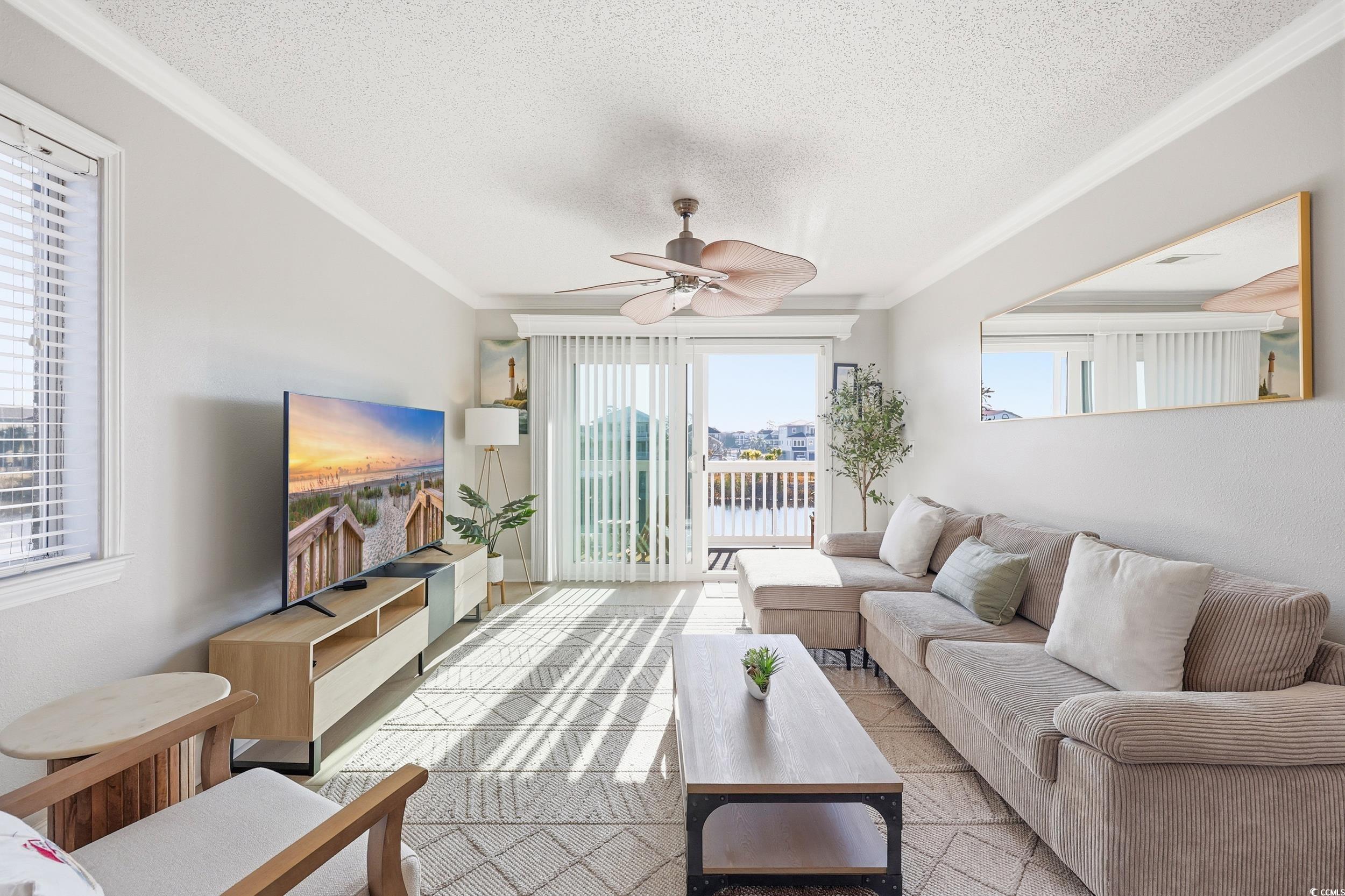 Living room featuring ornamental molding, a textured ceiling, and a ceiling fan