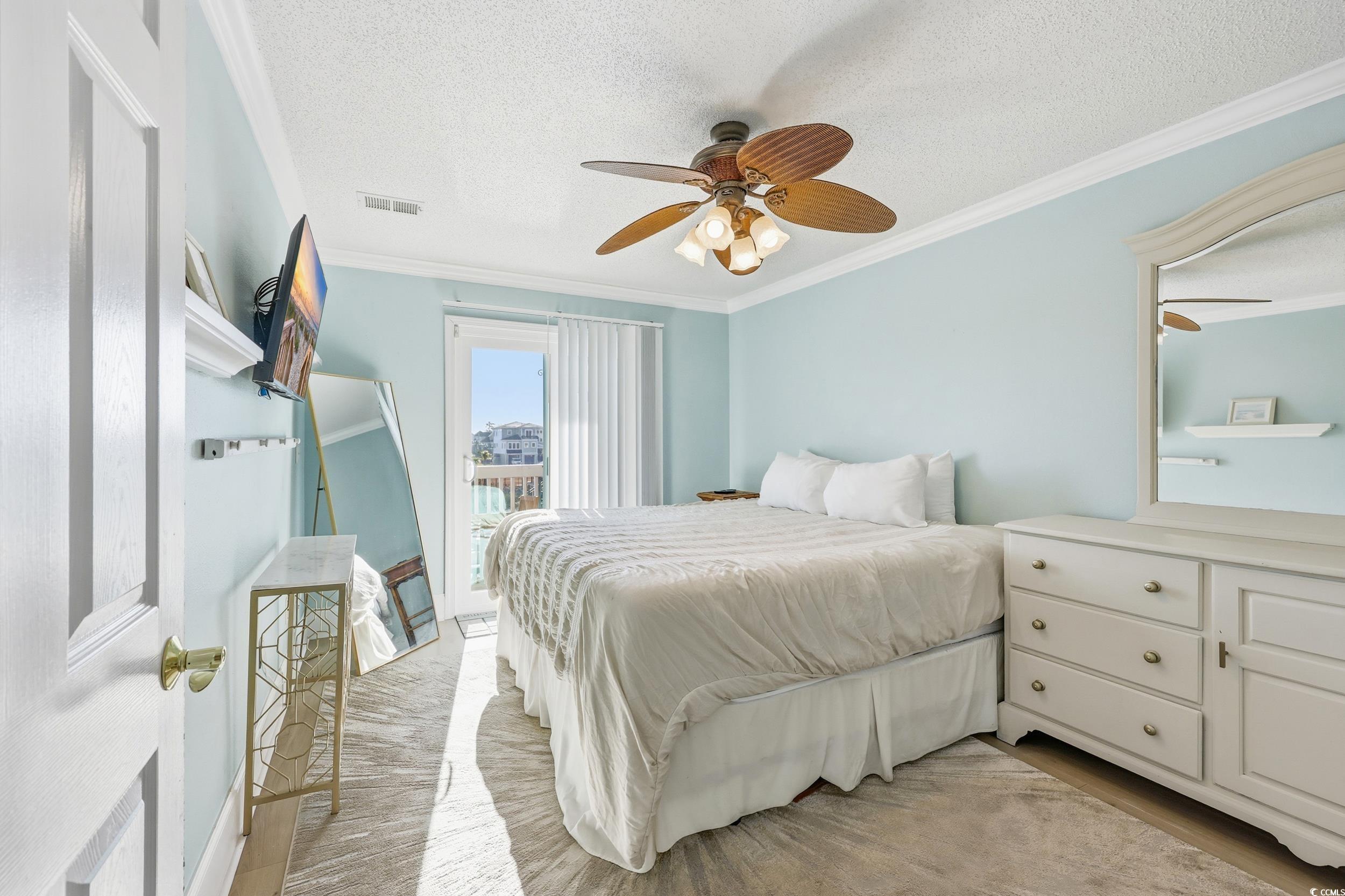 Bedroom with ornamental molding, a textured ceiling, and a ceiling fan