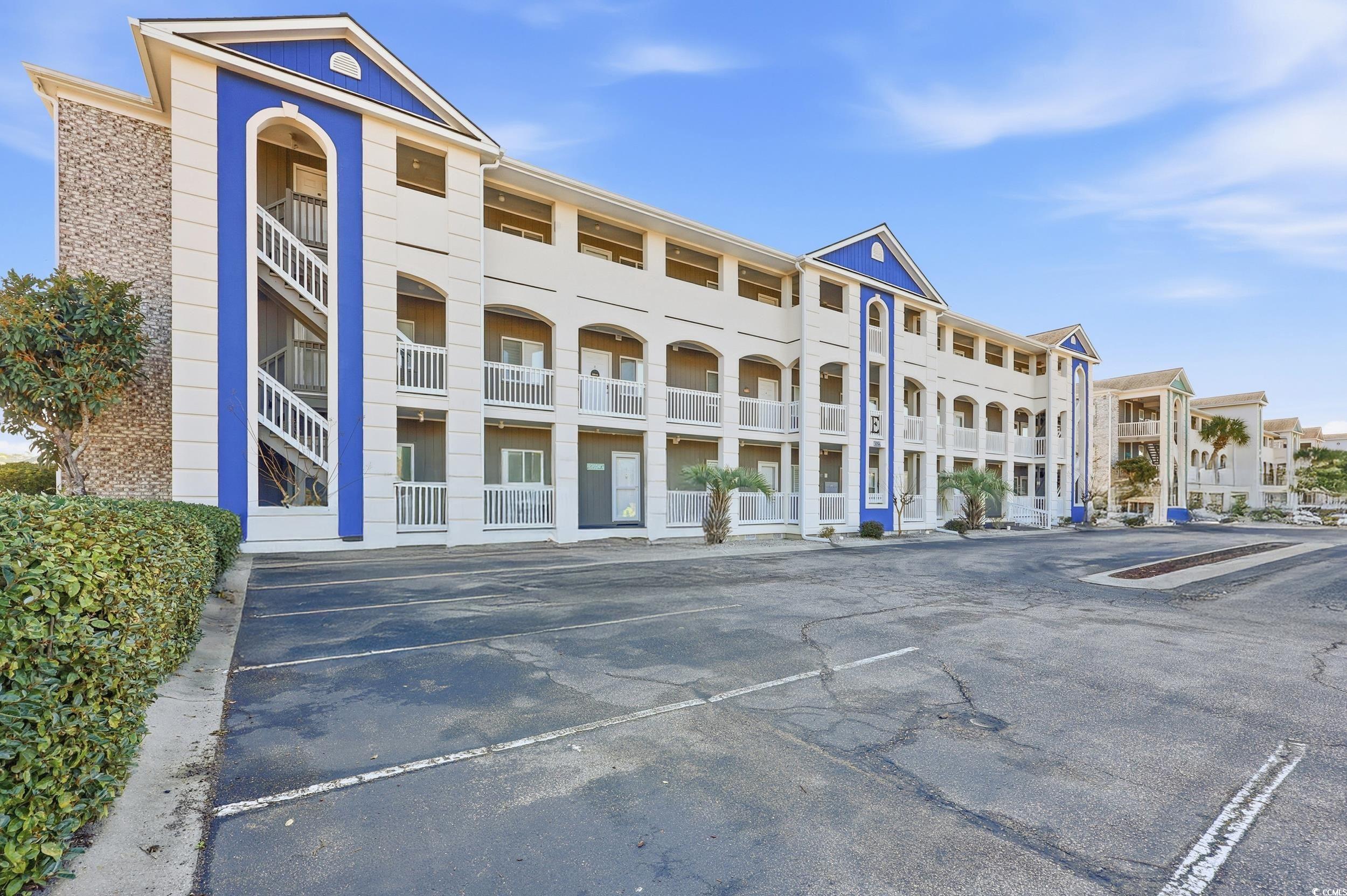 View of apartment building / complex with uncovered parking