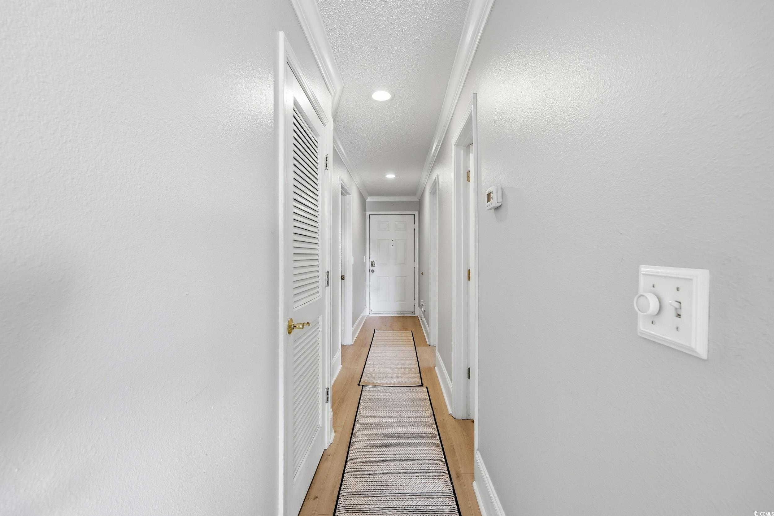 Hallway with light wood-style floors and recessed lighting