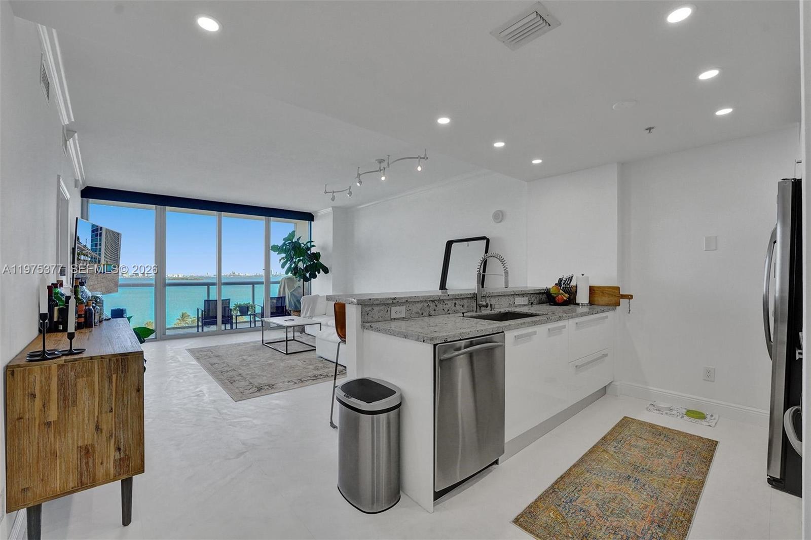 Unobstructed, breathtaking bay views welcome you the moment you step into this highly sought-after and largest one bedroom line in the building. This spacious unit features marble floors throughout and thoughtful upgrades including blackout and sheer roller shades, a new washer and dryer, oversized kitchen sink, extended granite countertops, and a custom real-wood primary closet with built-ins.The modern kitchen offers sleek cabinetry and stainless steel appliances, flowing seamlessly into the living area to maximize space and those stunning water views. The primary bath includes dual contemporary sinks and a generous soaking tub/shower combination.Enjoy resort-style amenities: 24-hour front desk and valet, convenience store, state-of-the-art fitness center overlooking the bay, multiple heated pools, theater room, party room, kids’ room, business center, and an innovative parking system. Spacious storage locker included.Ideally located north of Edgewater, perfectly positioned between Wynwood, the Design District, and Miami Beach. One of the few one-bedroom residences in the building offering two parking spaces its a rare Miami luxury.