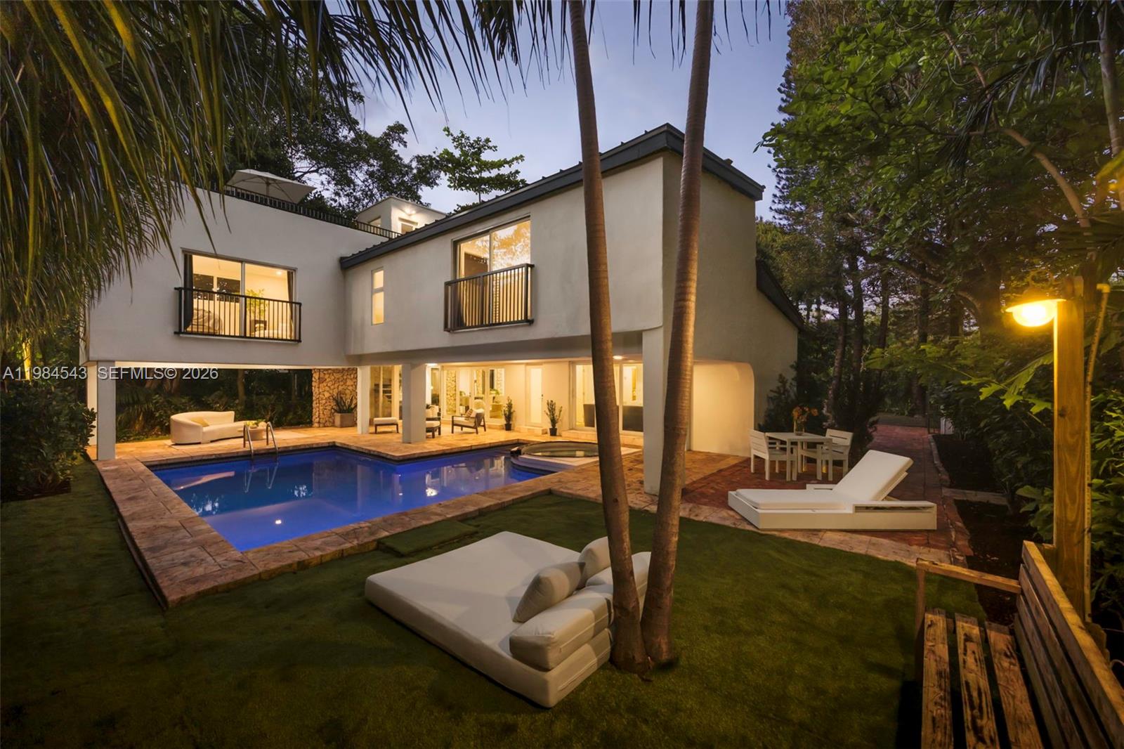 Thoughtfully remodeled mid-century residence on a prominent corner lot in South Coconut Grove, not in a flood zone, just minutes to top-rated public and private schools, parks, marinas, and the village. Gated 4BD/4BA with split layout: 2 bedrooms on the main level and 2 upstairs with ensuite baths. New 2025 metal roof and full impact glass complement wide plank European oak floors throughout. Light-filled interiors open to a spacious covered terrace for seamless indoor-outdoor living, ideal for al fresco dining and entertaining. Private backyard with pool, spa, lush canopy and fruit trees, plus rooftop retreat and timeless coral rock detailing.