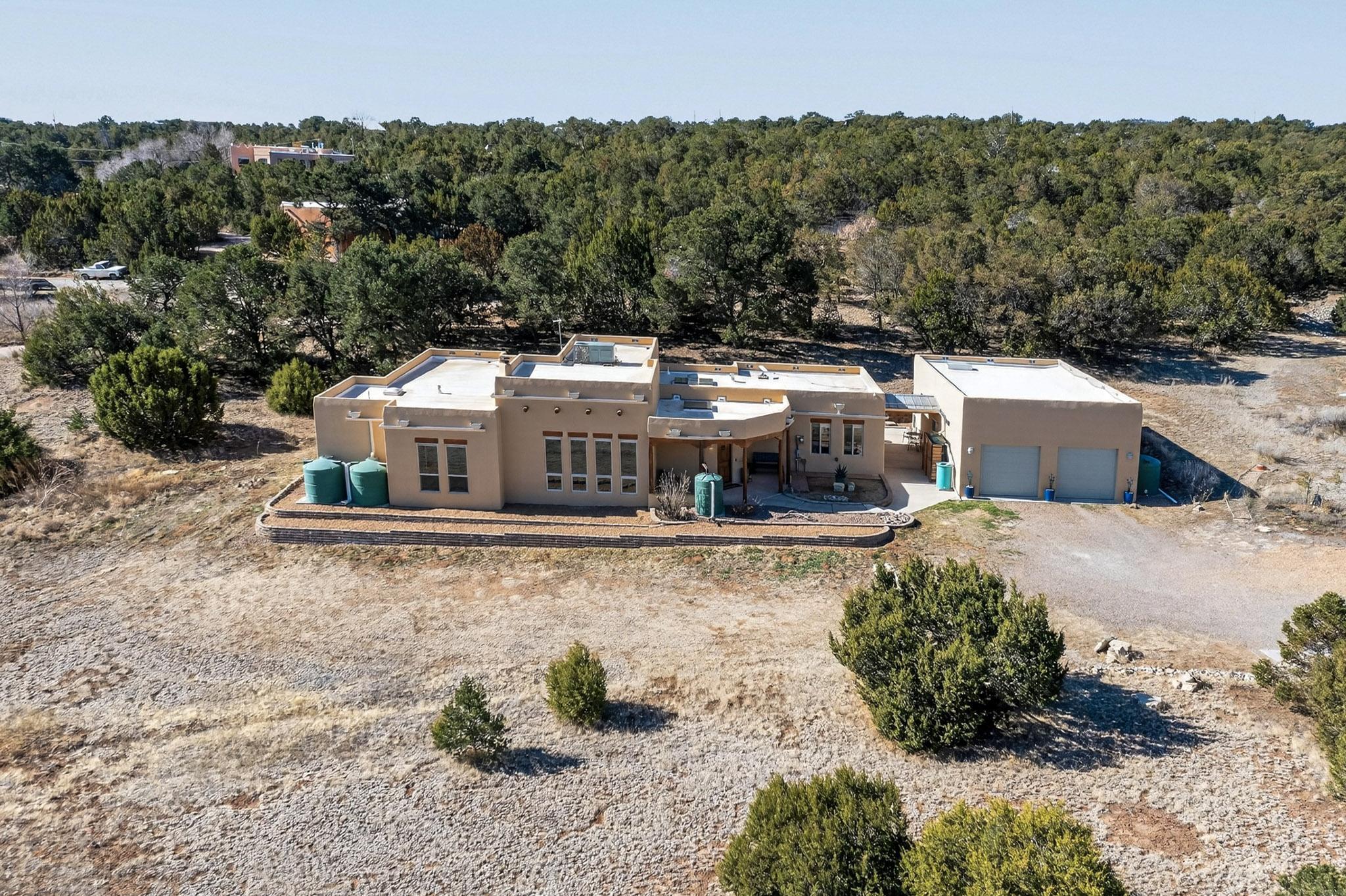 Spectacular 3-bedroom home on a 2.39-acre corner lot in the picturesque Sandia Mountain Ranch area. Beautifully crafted home offers exceptional upgrades throughout. Main living room features a custom kiva fireplace, while family/flex room includes a cozy pellet stove. Stunning kitchen boasts hickory cabinets, new granite countertops & backsplash, all stainless steel appliances, microwave drawer, and abundant storage added in last year and a half. Spacious primary suite offers a walk-in closet and spa-like bath with dual vanities, jetted tub, and tiled shower. LVP and tile flooring throughout; no carpet. Entranosa Water, New rainwater harvesting system (2026), and a 26'x40' detached 3-car tandem garage with 220V and heated workshop. Serene East Mountain living with city amenities nearby.