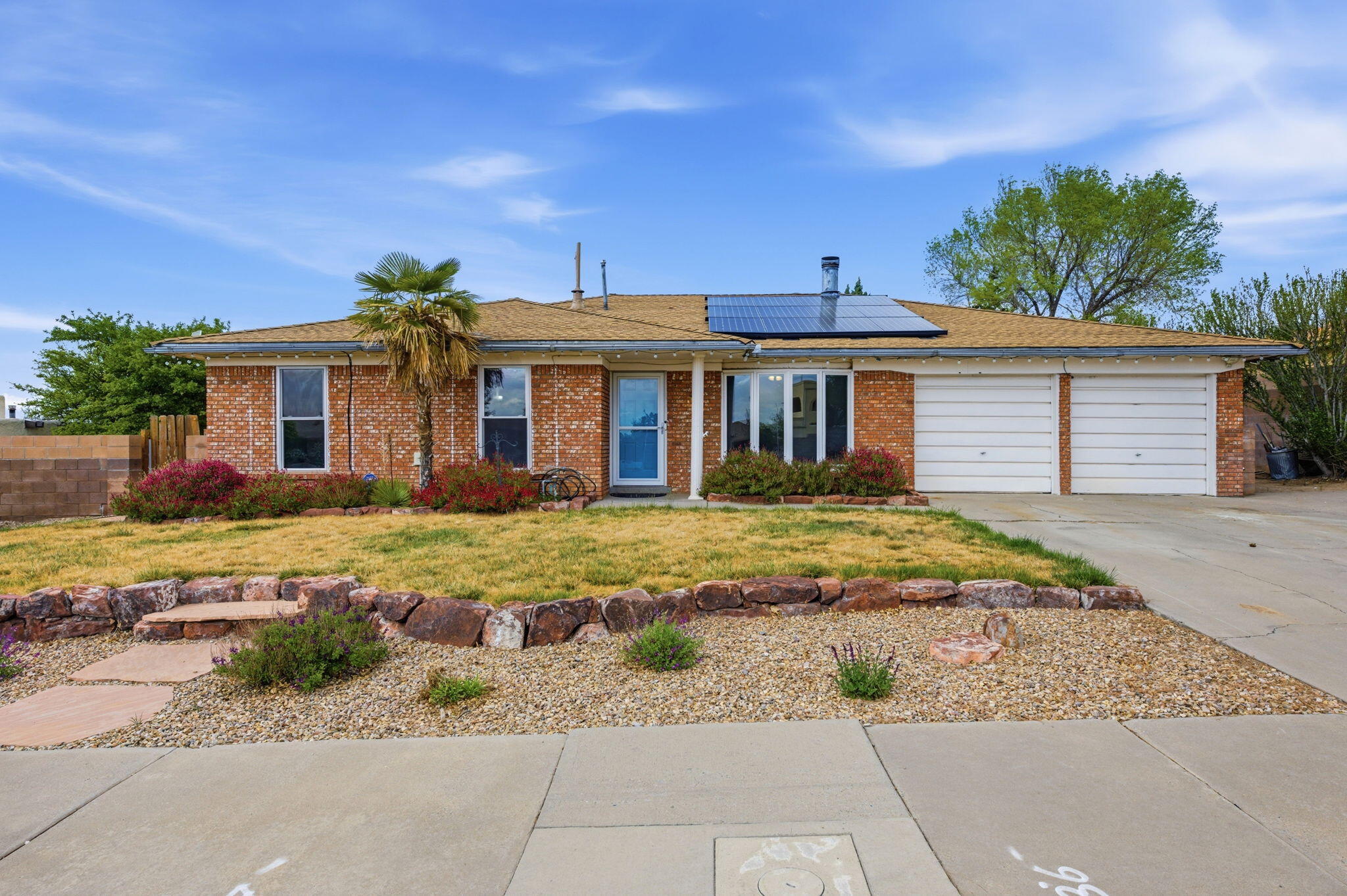 True single-story One block from the park! This beautifully maintained 4-bedroom home offers a spacious layout with both a welcoming front living room and an open-concept great room centered around a stunning fireplace--perfect for gathering. The home features new flooring throughout along with a new AC and furnace, giving buyers modern comfort. The bright and open kitchen flows seamlessly into the main living space, creating an ideal setup for everyday living. Step outside to enjoy a beautiful covered patio, garden beds ready for planting, mature fruit trees, and a large outdoor shed for extra storage. Both the front and backyard offer lush grass areas, providing space to relax. Energy-efficient solar panels add long-terms savings and value to this impressive property.