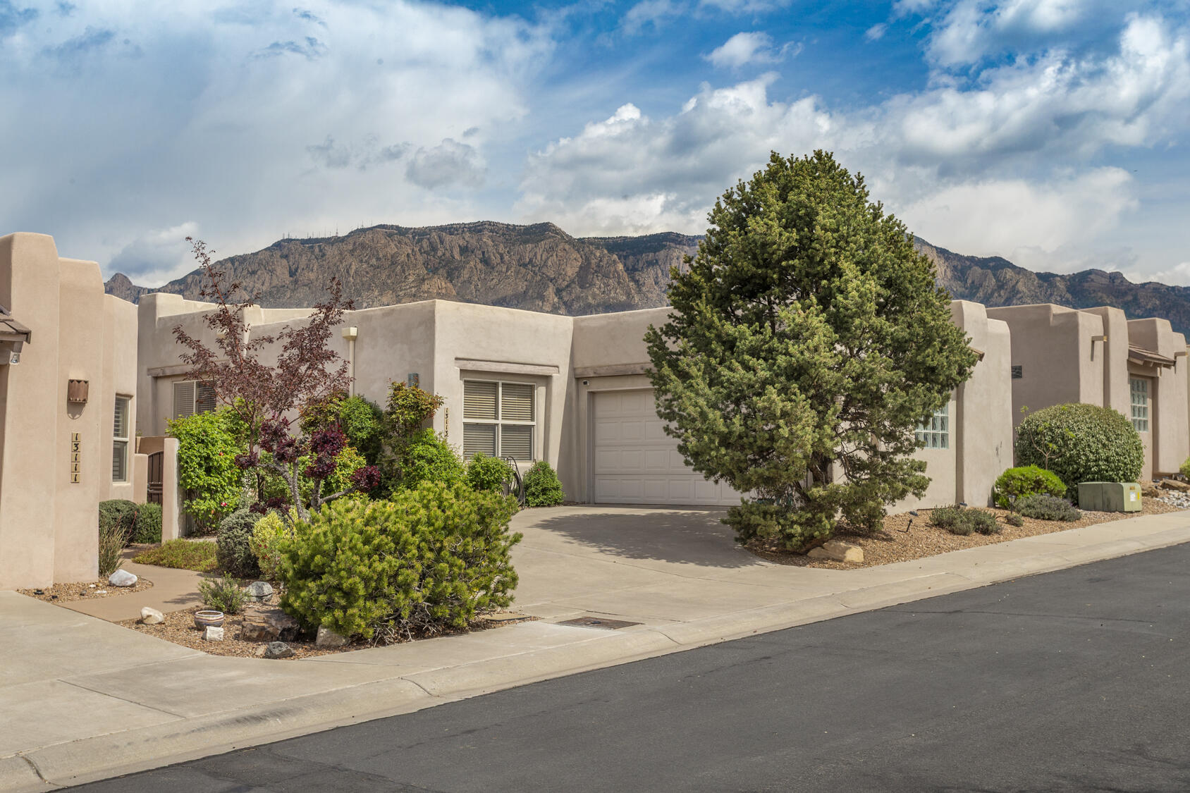 This single-level, 3-bedroom home is well sited in a desirable High Desert gated enclave, offering stunning mountain and city views. A beautifully maintained patio home, it features  updated kitchen stone counters and appliances, plus a new roof and solar panels and a 2-car epoxy finished garage.. An electric water heater and refrigerated air provide comfort and efficiency. The open floor plan is highlighted by 14-foot-high windows in the great room, dining area, and patio, showcasing Sandia Mountain sunsets. A lovely patio off the main living area is perfect for outdoor entertaining. The primary suite offers a spa bath and a large walk-in closet. The lush, mature landscaping is low-maintenance, and the home is conveniently located near trailheads and the High Desert park. A must see!