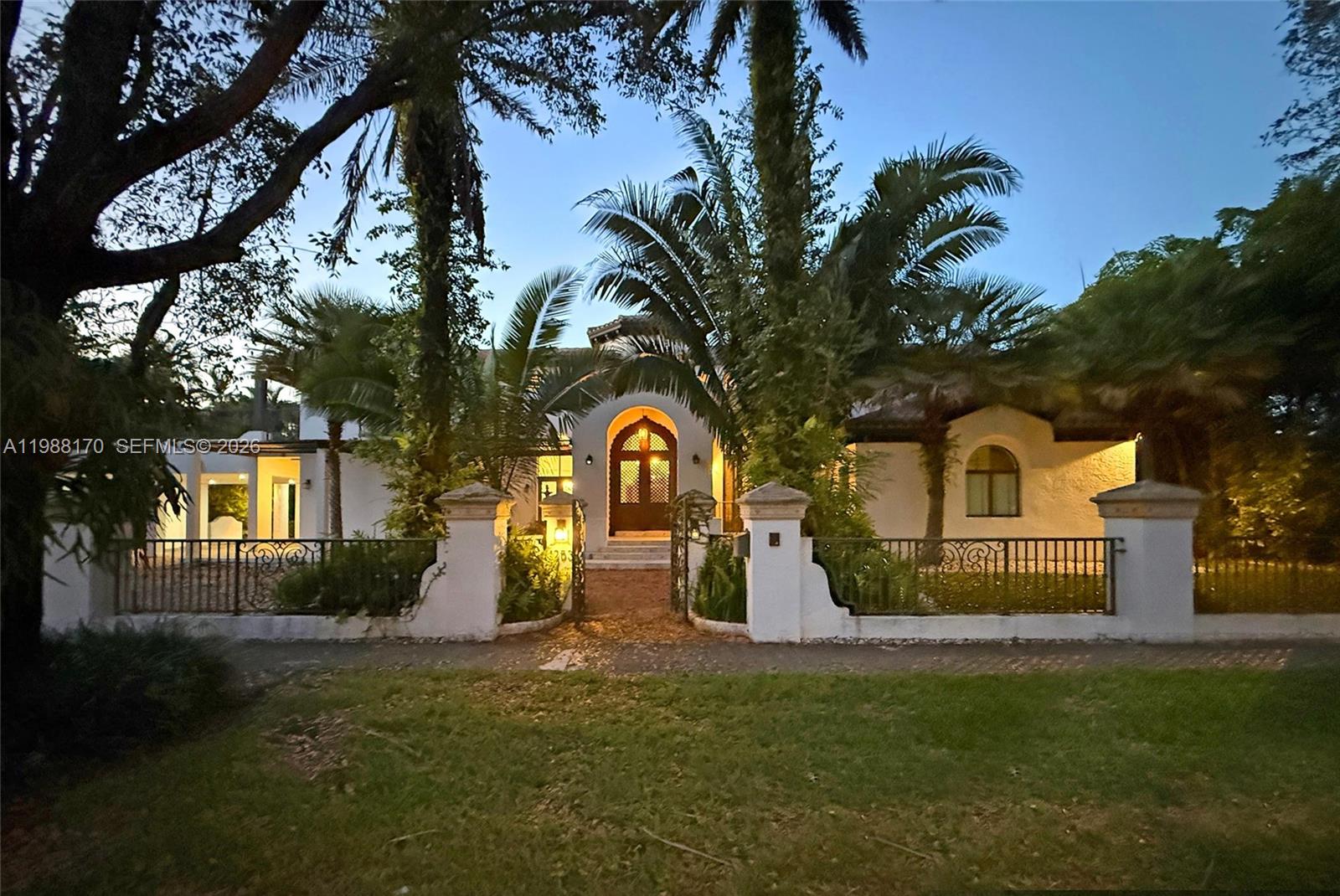 Behind wrought-iron gates on one of Coral Gables' finest streets stands a one-of-a-kind Mediterranean estate. Custom-built in 2002, this 6-BD, 6-BA masterpiece offers 6,887 SF on a 19,750 SF lot — where Old World grandeur meets South Florida resort living.A Moorish-arched portico leads to a breathtaking hand-carved lattice mahogany entry door beneath an amber lantern a work of art before you even step inside. The soaring octagonal rotunda beyond features a hand-painted sky mural, wrought-iron chandelier, travertine floors, coral stone columns, pecky cypress beam ceilings, and a monumental hand-carved travertine fireplace.The chef's kitchen opens to pool views. A full-width covered loggia with wood-plank ceiling bridges interior and exterior living seamlessly. The resort pool features LED lighting, a cascading waterfall wall, and a travertine deck surrounded by lush tropical landscaping. A private turf sports court and dedicated fitness room with all exercise equipment included complete this extraordinary compound.Two kids' suites connect through a shared loft play and study space — a magical private world for young ones. Six generous suites total, hand-painted ceiling murals, Portuguese-tile baths, and rich mahogany millwork throughout. Minutes to Miracle Mile, Merrick Park, and MIA.