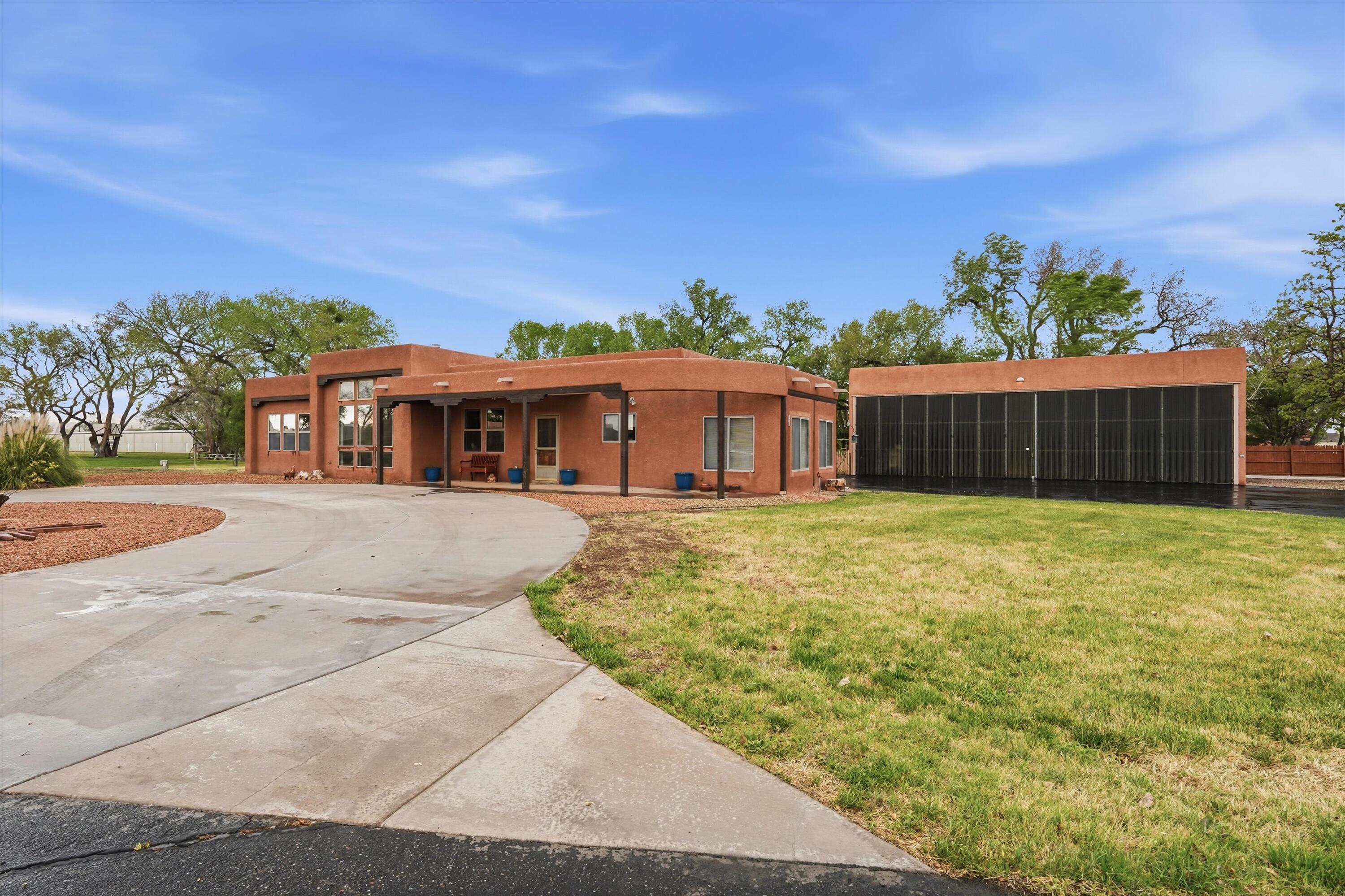 40x48 insulated hangar with Icynene insulation, durable 2x8 construction, and bi-fold doors sets the tone for this pilot-friendly Southwest retreat in Mid Valley AirPark, Los Lunas. Taxi from your home to the runway and enjoy true fly-in living. This beautifully landscaped corner-lot home offers vaulted ceilings, abundant natural light, and classic SW charm with wood beams, nichos, and a Kiva fireplace. The spacious kitchen provides ample counter space and cabinetry. The primary suite features a large bath with double sinks and a walk-in closet. Includes refrigerated air, skylights, and ceiling fans. Versatile office or hobby room can serve as a 4th bedroom. Oversized 2-car garage with storage home includes gray water system.  Paid off solar panels included!  Ask about 20K flex cash!
