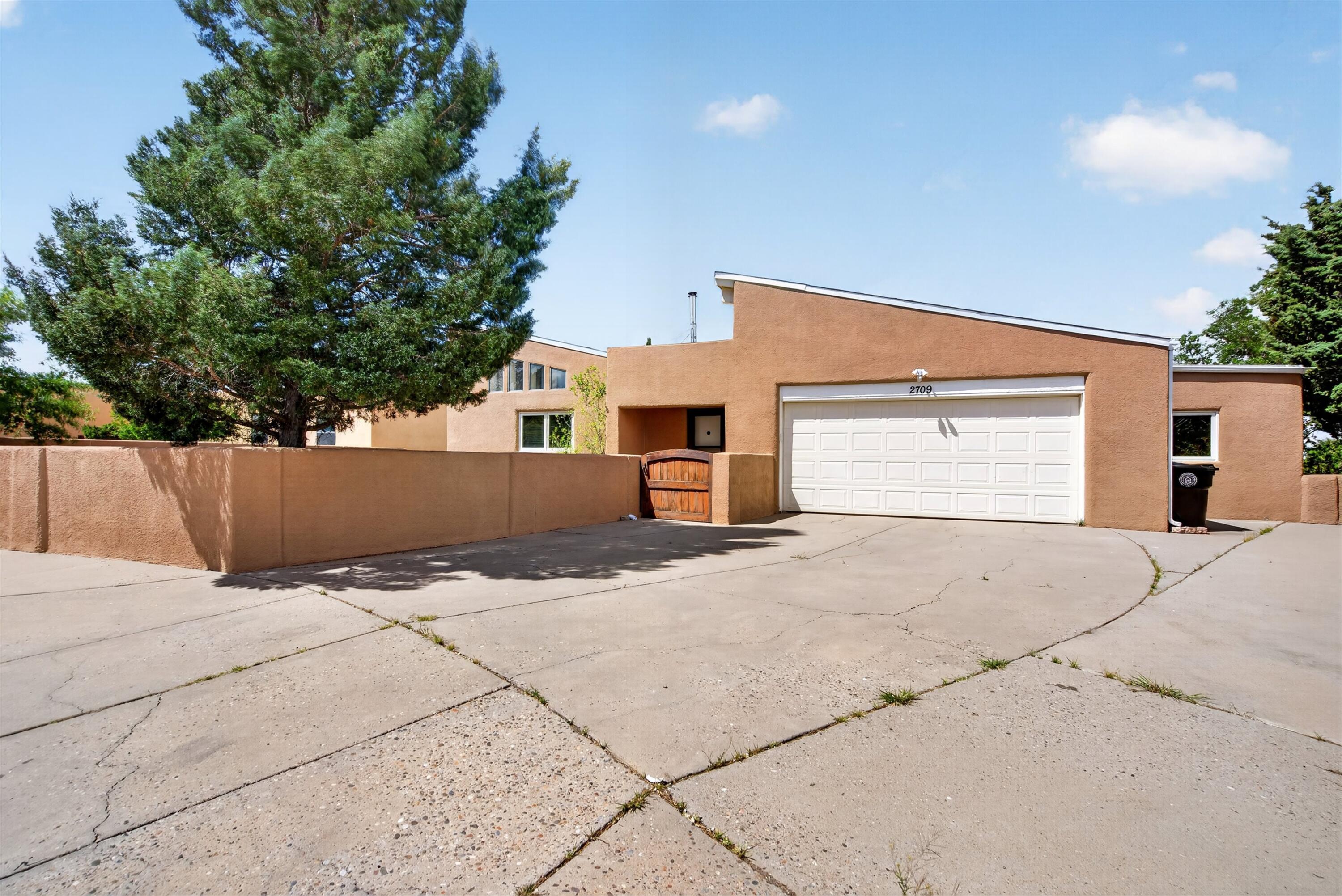 Welcome home to this beautiful Adobe home on a quiet cul-de-sac in Brentwood Hills with No HOA! Featuring vaulted ceilings with wood beams, custom built-in shelving, brick floors, abundant natural light, and a freestanding wood-burning stove. Enjoy ductless cooling/heating, a covered patio with scenic views, and easy access via the Tramway bridge right to the Sandias. Close to Lynnwood Park. Move-in ready with a  workshop, roof redone in 2018, and dual solar electric water heater. A true gem with timeless charm!