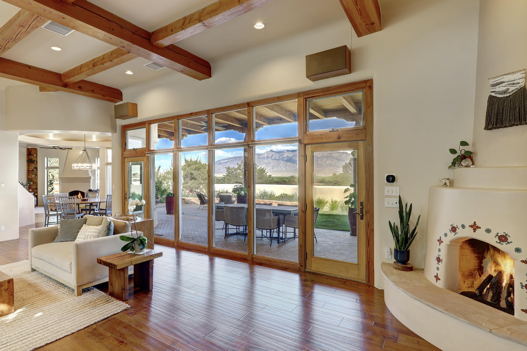 Stunning custom home w/ breathtaking views & upscale finishes throughout. Light-filled interior features soaring beamed ceilings & an open, flowing floor plan designed for comfort & elegance. Rich engineered wood & travertine flooring add warmth. Chef's kitchen shines w/ SS appliances, granite counters & walk-in pantry--ideal for daily living & entertaining. Multiple living areas w/ 2 fireplaces create a cozy yet refined feel. Nearly every window captures panoramic views, blending indoor/outdoor living. Recent upgrades include TPO roof, stucco & 3 HVAC units, among many others. Lush landscaping w/ greenhouse, raised beds & basketball court. Enjoy colorful Sandia sunsets from the expansive, relaxing backyard portal. A true treasure in a prime location close to all amenities.