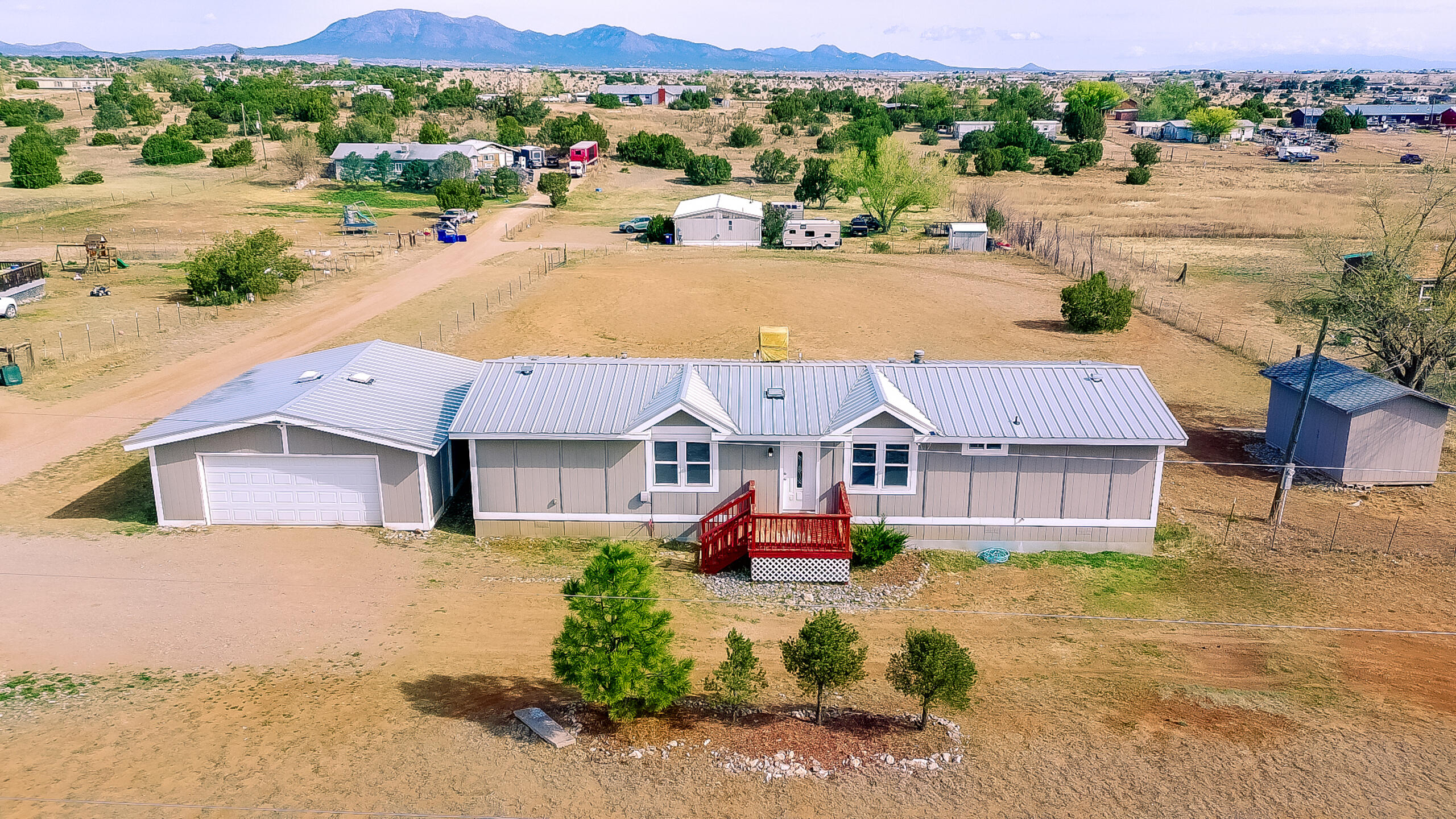 Fantastic property on over 1 acre in Edgewood, NM! Open floor plan with spacious dining area and cathedral ceilings throughout. Updated kitchen features shaker-style cabinetry, stainless steel appliances, granite countertops, pendant lighting, recessed stainless steel sink, and upgraded brushed nickel faucet. Updated LVP flooring throughout all living areas with carpet only in bedrooms. Primary bath includes tub/shower combo with custom tile surround, updated vanity, countertop, and plumbing fixtures, plus dual closets. Secondary bath offers tub/shower combo with custom tile surround, updated vanity, and updated plumbing and lighting. Upgraded interior doors with modern hardware. Fully fenced yard with large front and rear decks offering valley and mountain views. Oversized detached 2-car