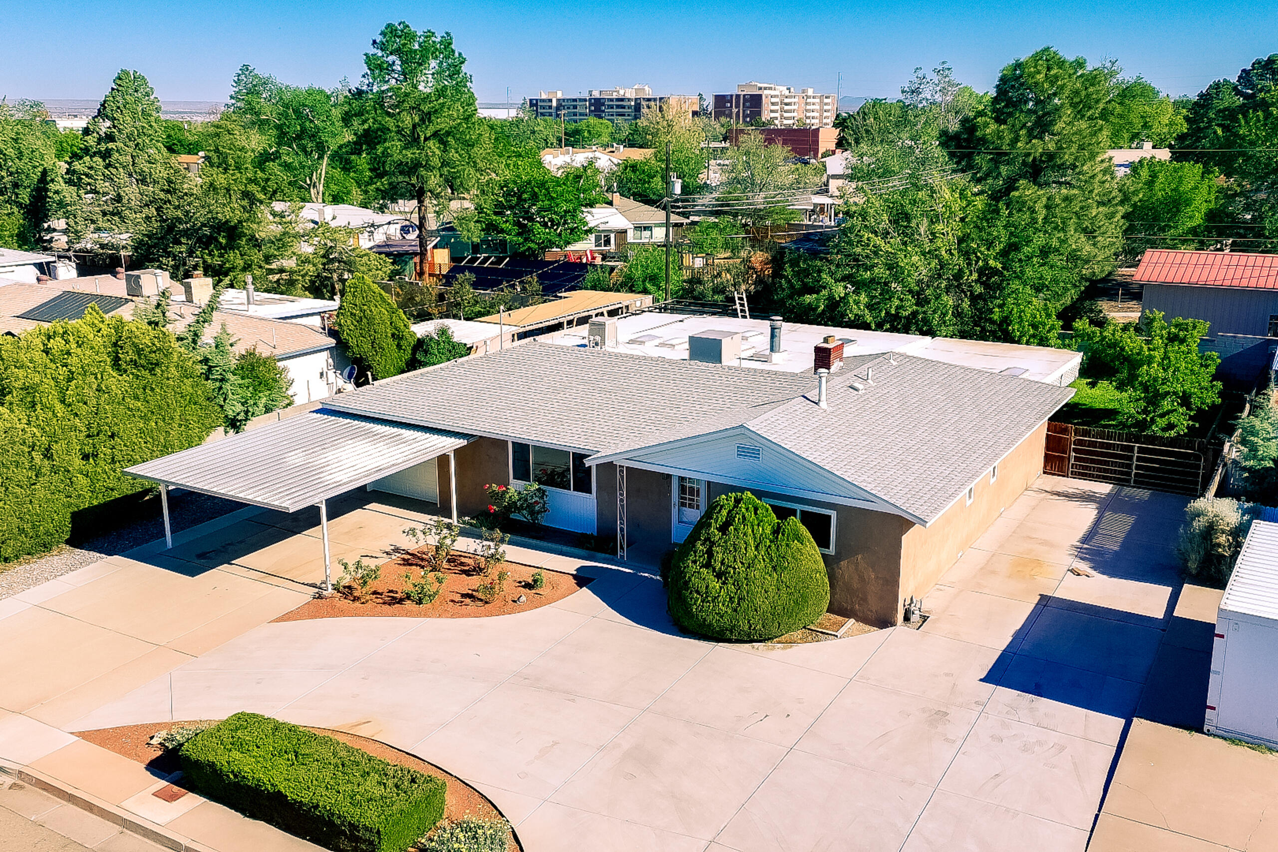 Fabulous upgraded Mossman home in NE ABQ featuring approx. 2,794 sq ft w/ 3BR, 2BA, 1-car garage, oversized 2-car carport, backyard access, RV parking, circular driveway. Open floor plan w/ tons of natural light & original refinished hardwood floors. Fully remodeled kitchen features shaker cabinetry w/ soft-close hinges/drawers, granite countertops, oversized island w/ breakfast bar & gas cooktop, built-in SS oven/microwave, updated SS dishwasher, recessed SS sink, walk-in pantry & appliance closet. Office w/ outside access, spacious laundry room & walk-in storage closet. Remodeled primary bath, updated hall bath, upgraded vinyl thermal dbl-pane windows, upgraded 200-amp service, TPO roof on addition July 2025, large covered patio, fruit trees & raised garden beds w/auto drip irrigation.