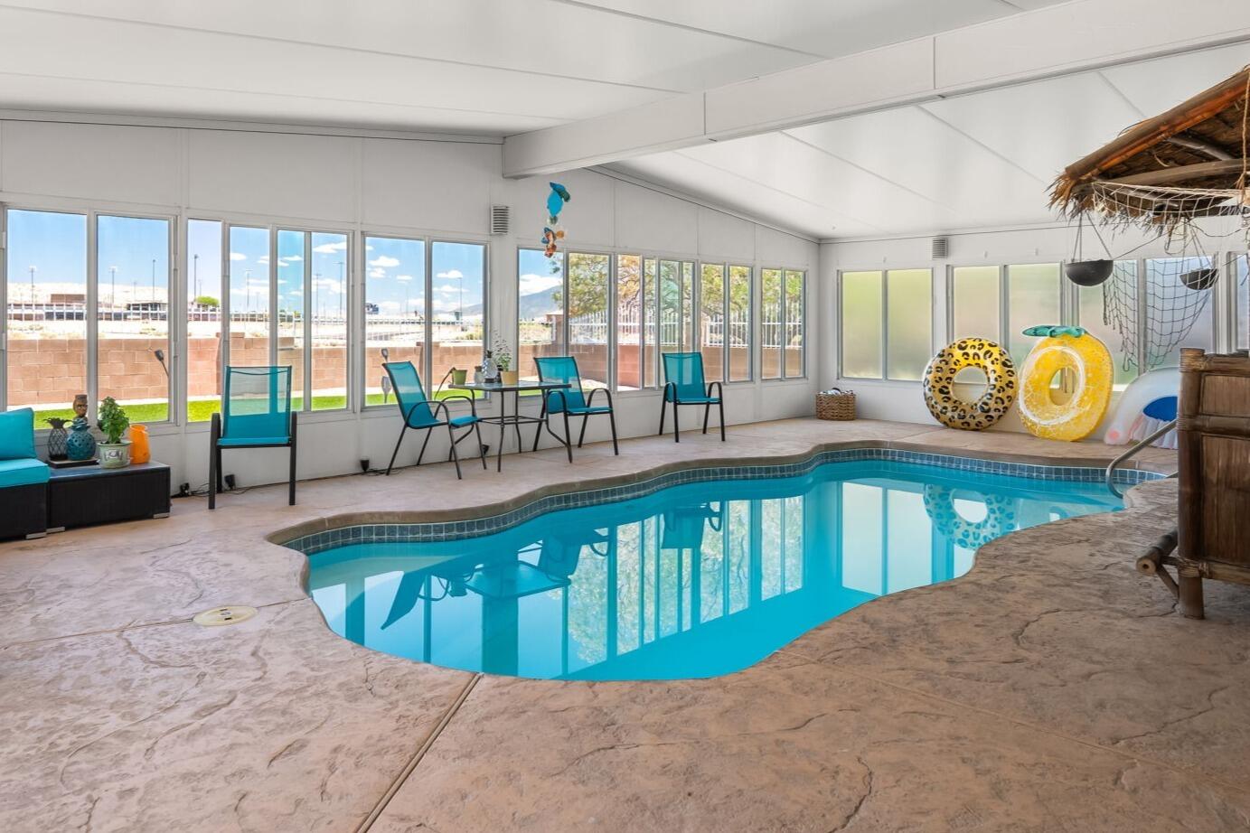 Imagine swimming year-round in your own sun-filled indoor heated pool, surrounded by walls of windows that bring in natural light and create a space designed for relaxation, exercise, and everyday enjoyment. This single-story home backs to open space, offering privacy, sunset skies, and Sandia Mountain views from the pergola-covered patio. Recent updates include new carpet, replaced poly pipes, refrigerated air, solar, and updated kitchen and baths. The attached 2-car garage, backyard access, and 50-amp RV service add flexibility for hobbies, vehicles, and storage. Conveniently located near Rio Rancho High School, High Resort Park, walking trails, dog park, sports fields, shopping, dining, and Target.