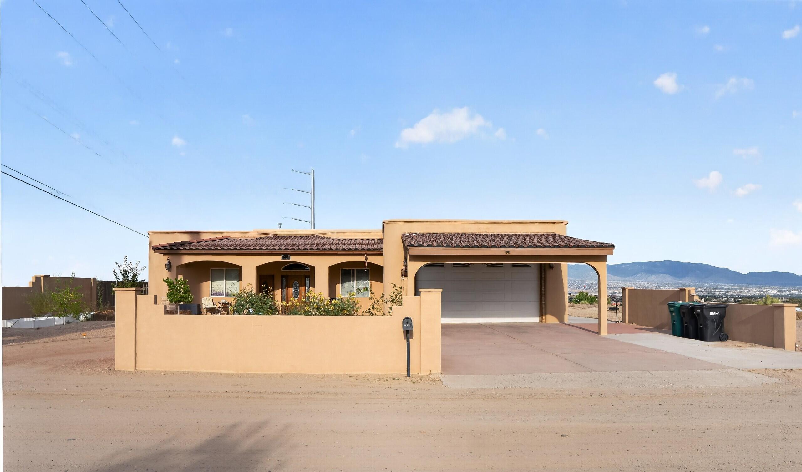 Perched high above Rio Rancho on a spacious half-acre lot, this 2,630-square-foot custom home delivers the kind of views that never get old. From glowing city lights at night to sweeping Sandia Mountain vistas, the setting is one of the home's standout features. Inside, the thoughtful custom design gives the home plenty of character, with architectural nichos, curved details, wide hallways, and an open, comfortable floor plan built for both everyday living and entertaining. The spacious kitchen opens directly to the main living area and features granite countertops, stainless steel appliances, abundant cabinetry, and wraparound bar seating that creates a natural gathering place. The outdoor living space is just as impressive. A massive covered patio with approximately 12-foot ceilings provides plenty of room to relax, entertain, dine outdoors, or simply enjoy the view. Beyond the patio, the oversized lot offers room to create the backyard you've been envisioning. One of the home's most unique features is the flexible second primary suite/in-law quarters with its own private entrance. The space could work beautifully for extended family, guests, a private office, studio, or other live/work arrangement.
