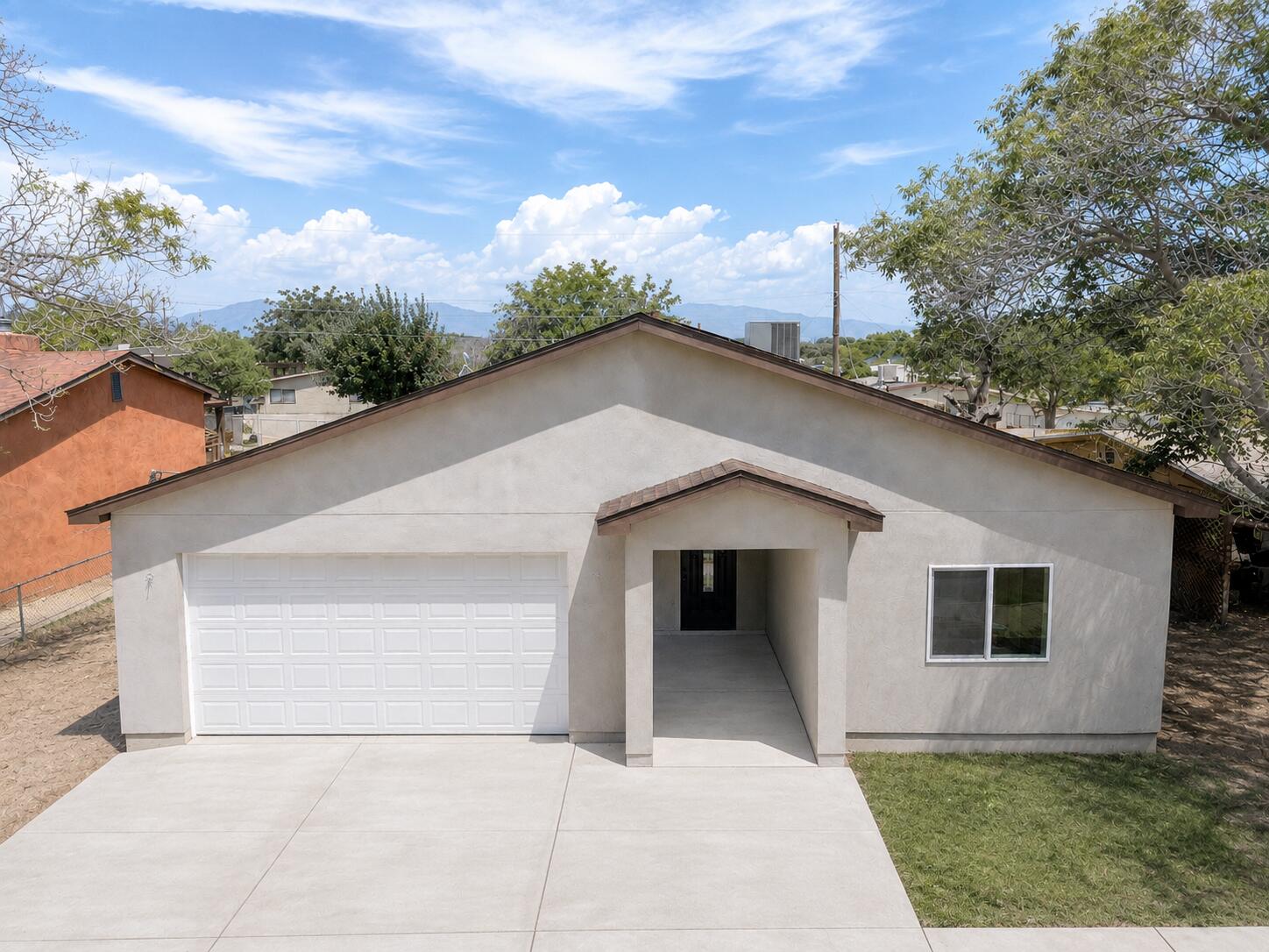 Single-story home with a white garage door, recessed entry, broad driveway, and distant mountain views.